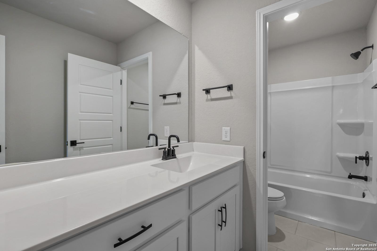 Modern secondary bathroom with double vanity, frameless shower, soaking tub in Davidson Homes The Brazos C, San Antonio