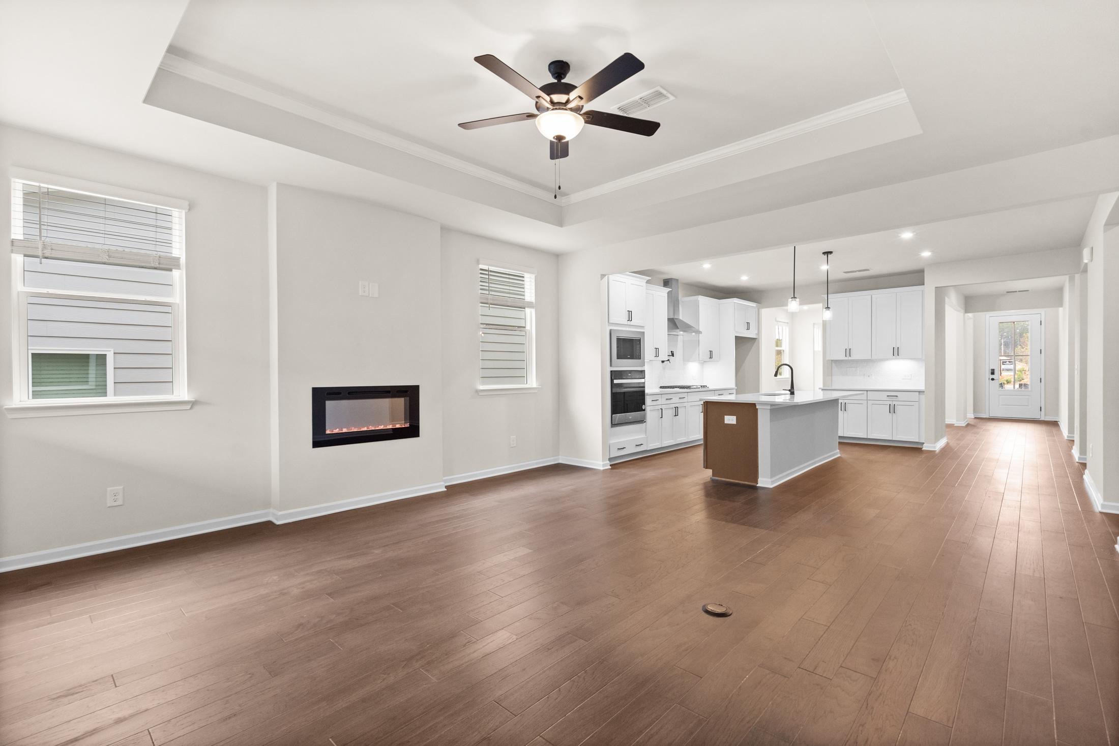 Open-concept living and kitchen in The Glenwood home with white cabinetry, large island, gas fireplace, and hardwood floors