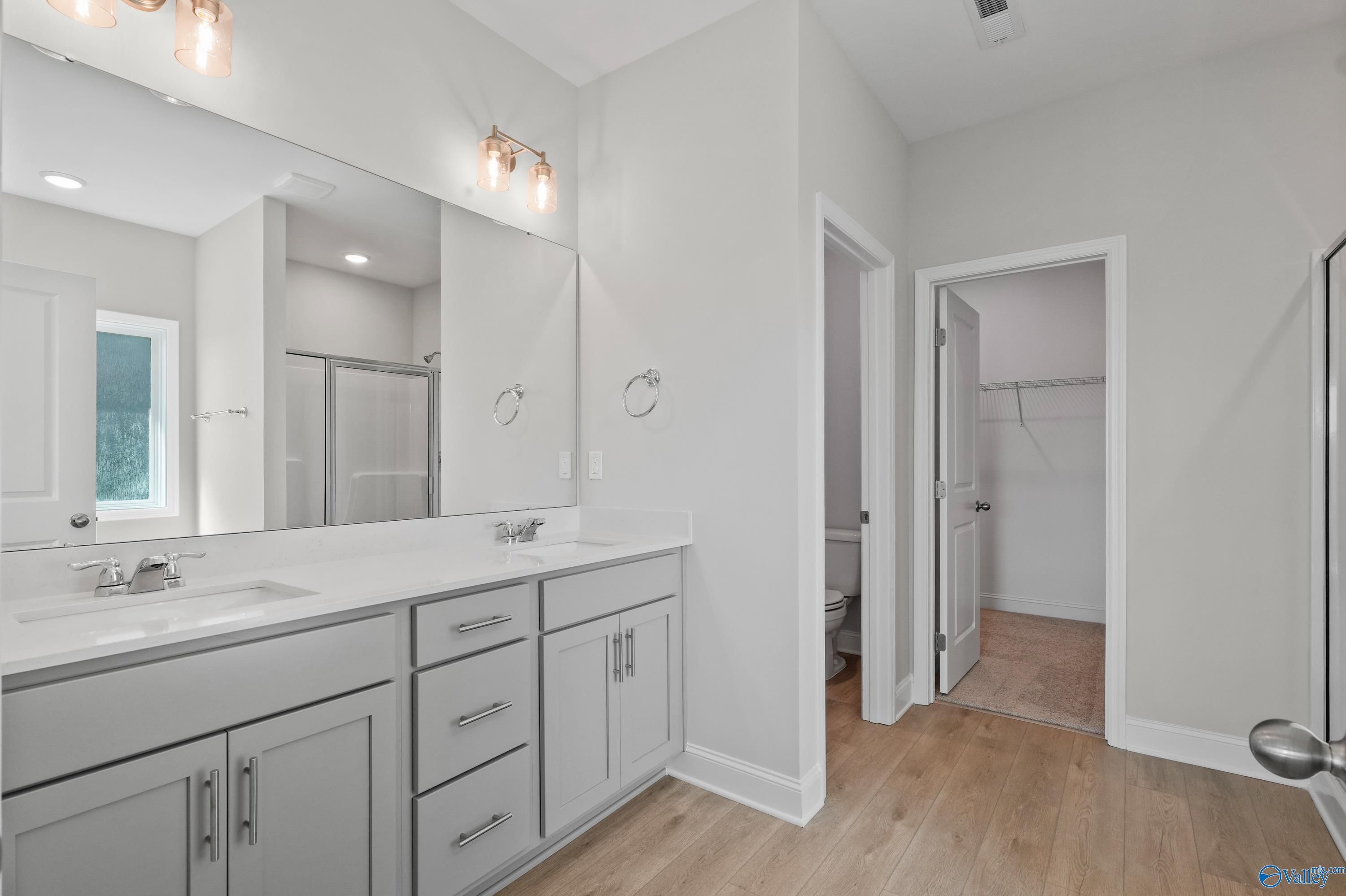 Modern master bathroom featuring double vanity, frameless shower, and walk-in closet in Davidson Homes The Everett, Hazel Green, AL