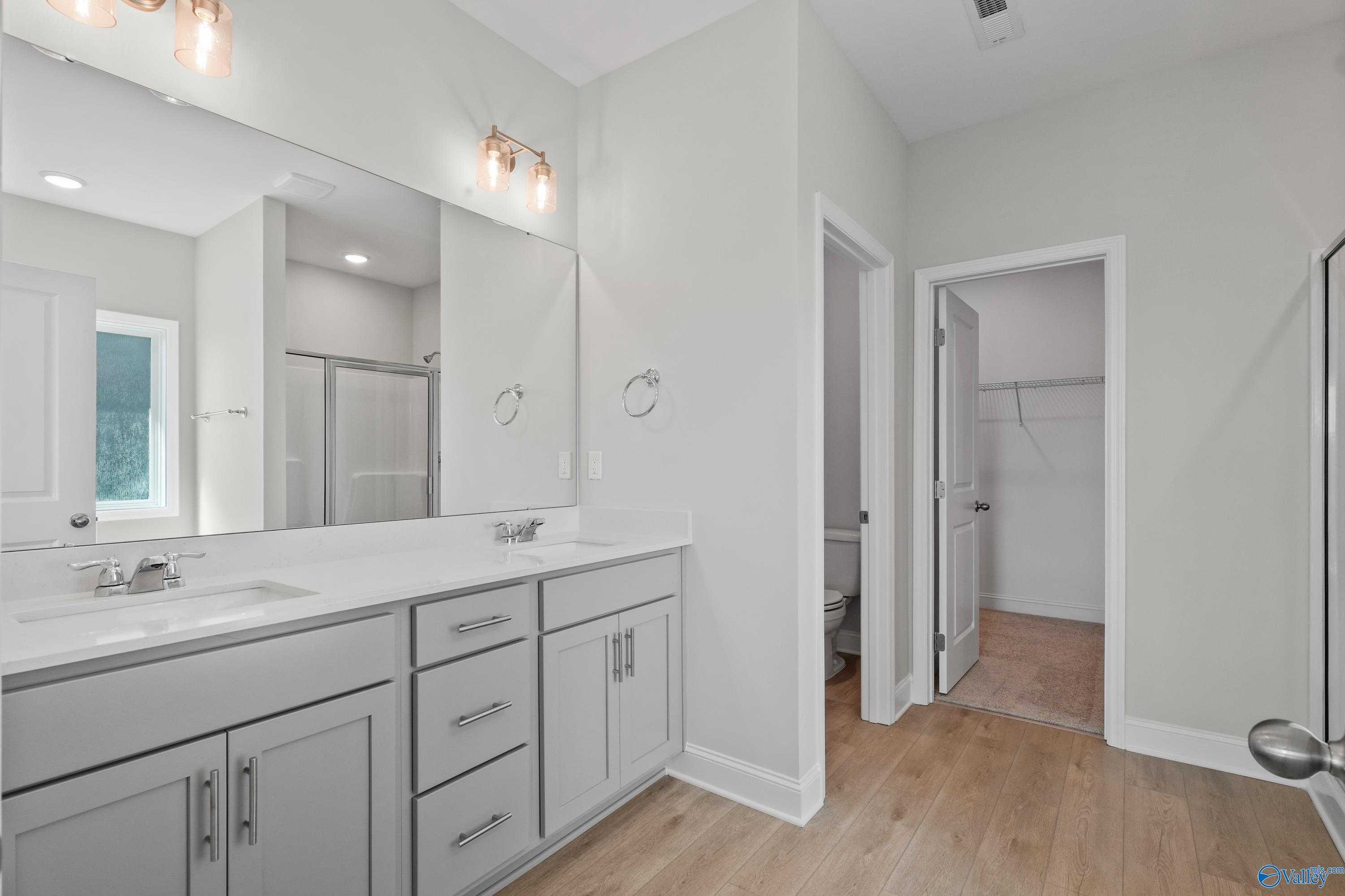 Modern master bathroom featuring double vanity, frameless shower, and walk-in closet in Davidson Homes The Everett, Hazel Green, AL