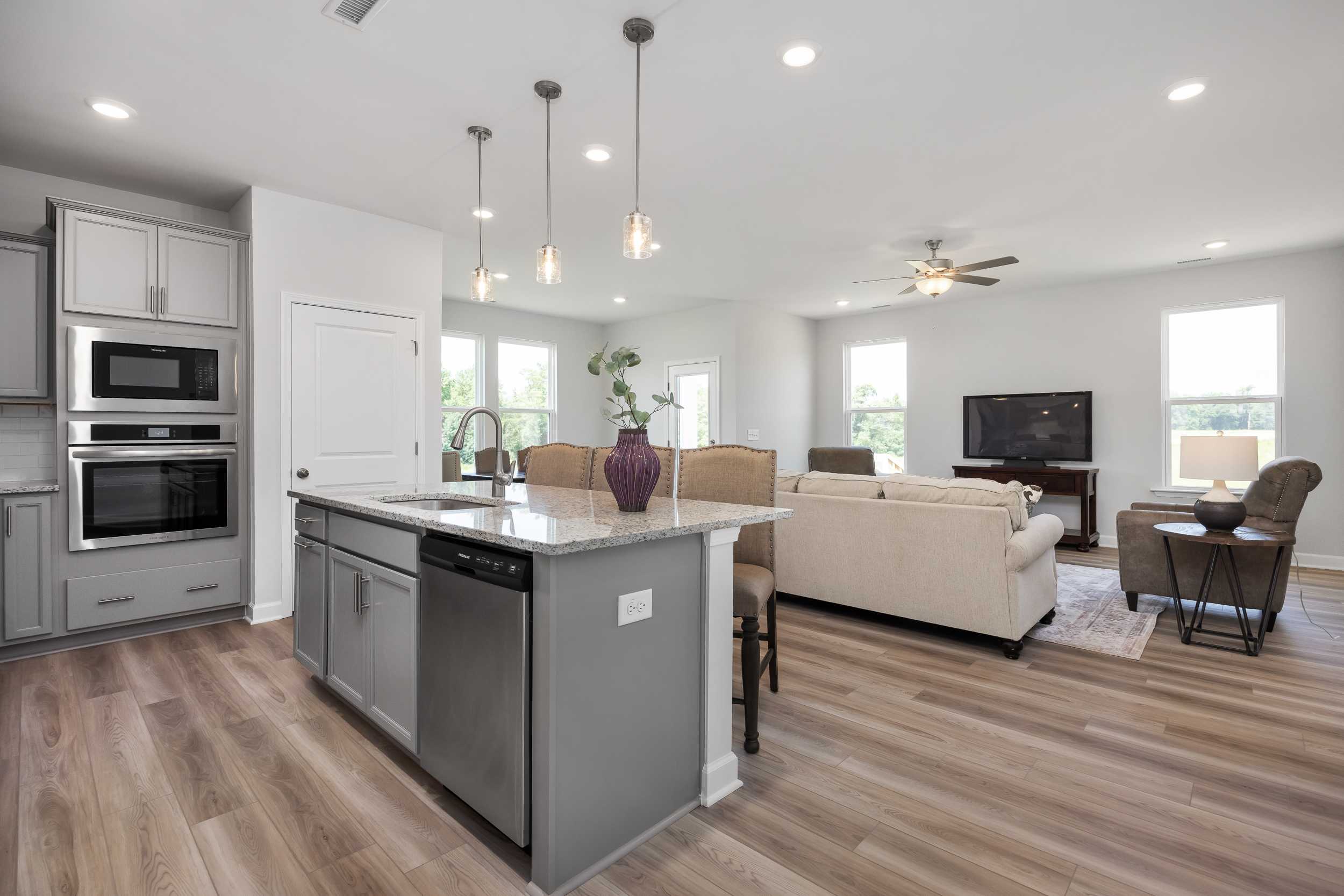 Open-concept kitchen and living room at Woodland Crossing in Zebulon NC with island, hardwood floors, pendant lights, and beige sofa