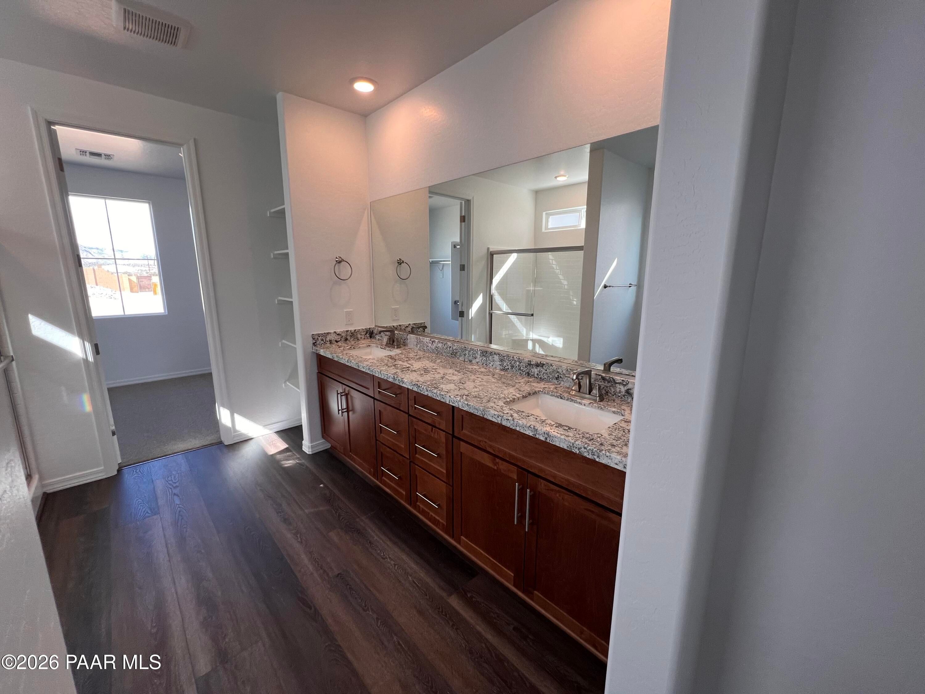 Modern master bathroom featuring double quartz vanity, frameless shower, and wood flooring in Davidson Homes The Monarch A, Prescott, AZ