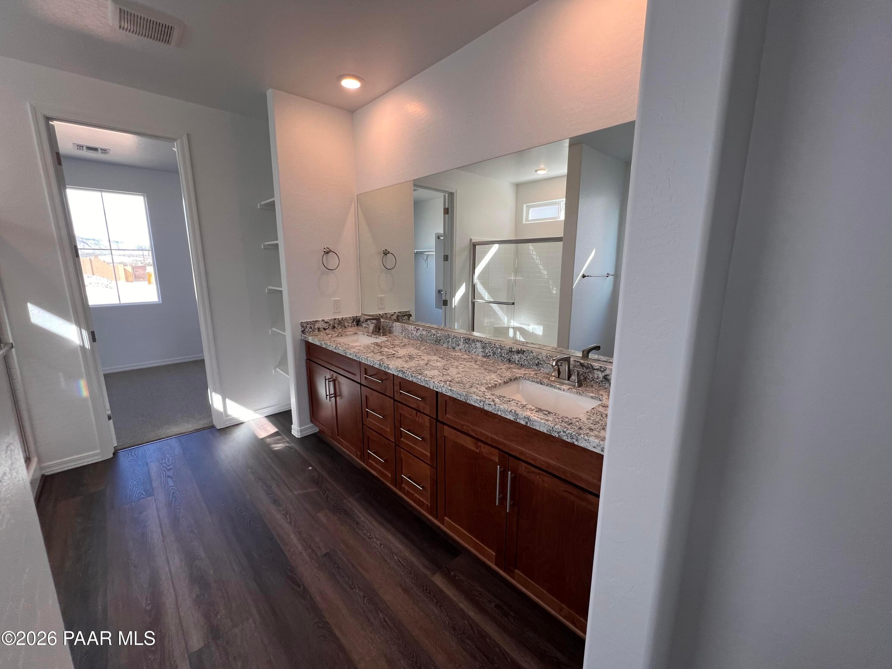 Modern master bathroom featuring double quartz vanity, frameless shower, and wood flooring in Davidson Homes The Monarch A, Prescott, AZ