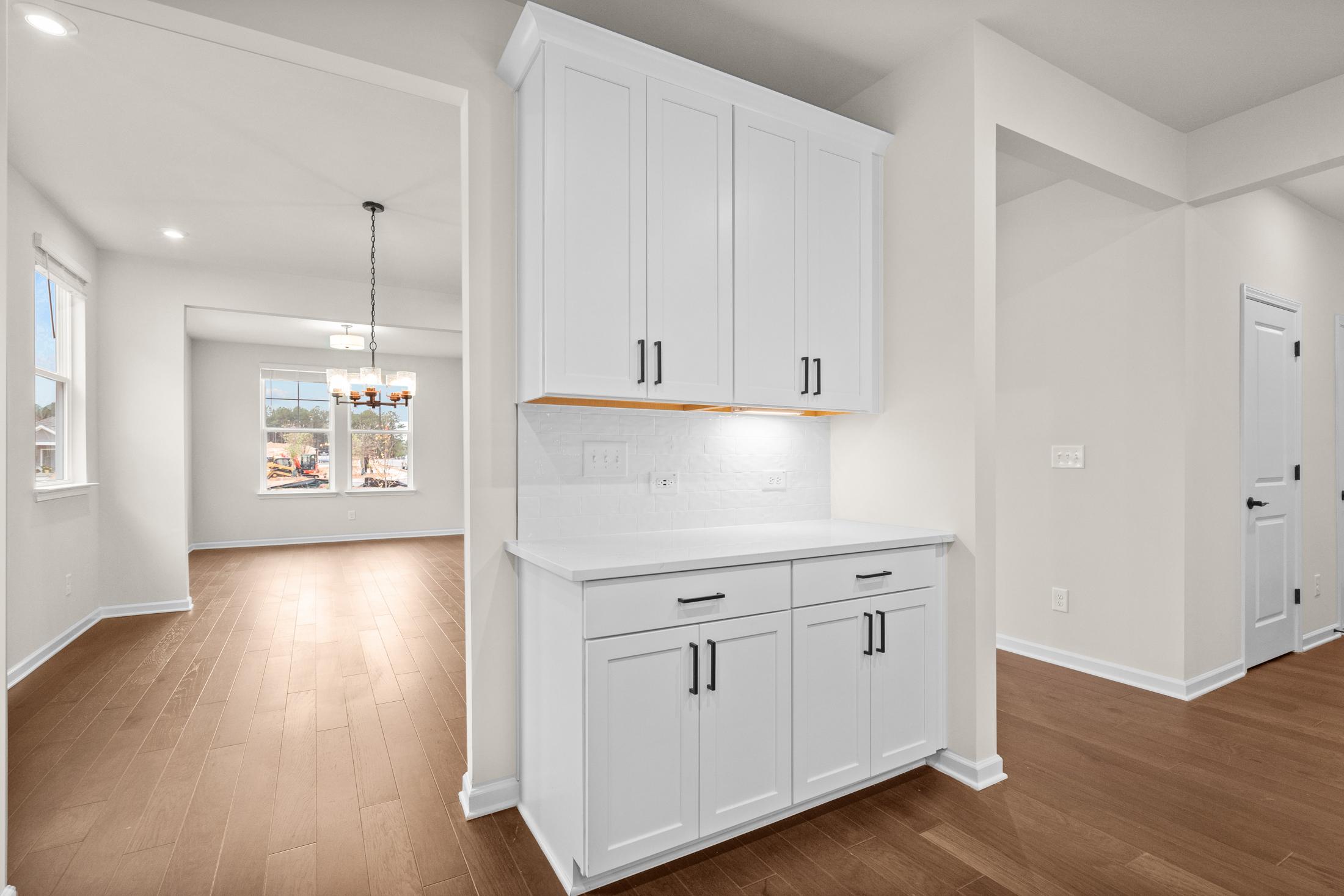 Modern kitchen pantry in The Glenwood home design featuring white shaker cabinets, sink, and hardwood floors