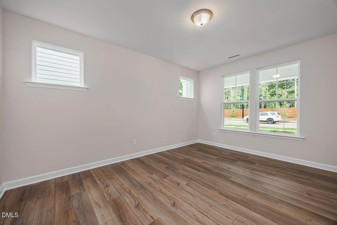 Bright, empty bedroom with wood-look flooring and natural light in The Hickory II C floor plan at Montrose, Aberdeen, NC.
