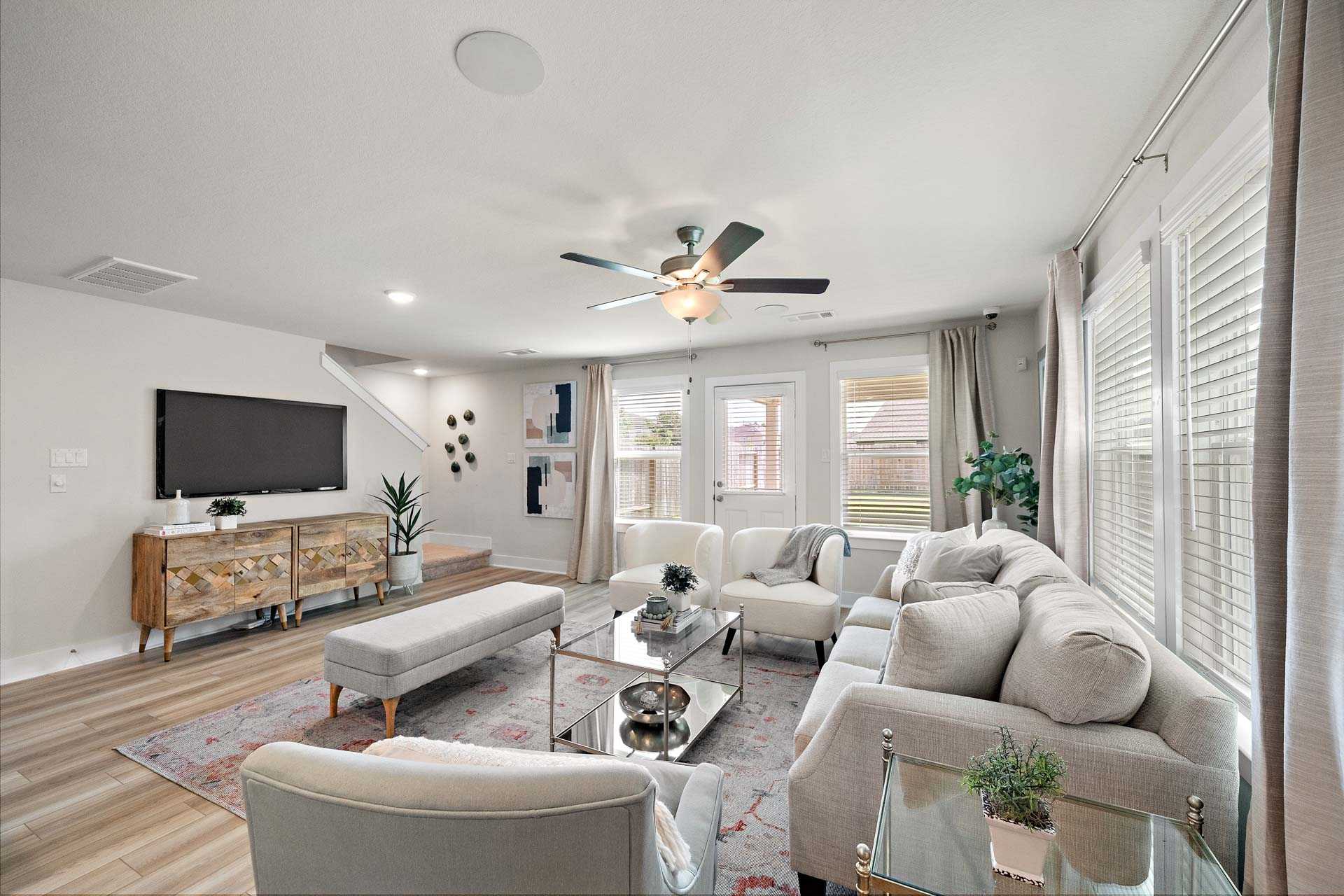 Cozy open-concept living room at Haven at Kieth Harrow in Cypress TX with hardwood floors, beige sofa, plants, and large windows