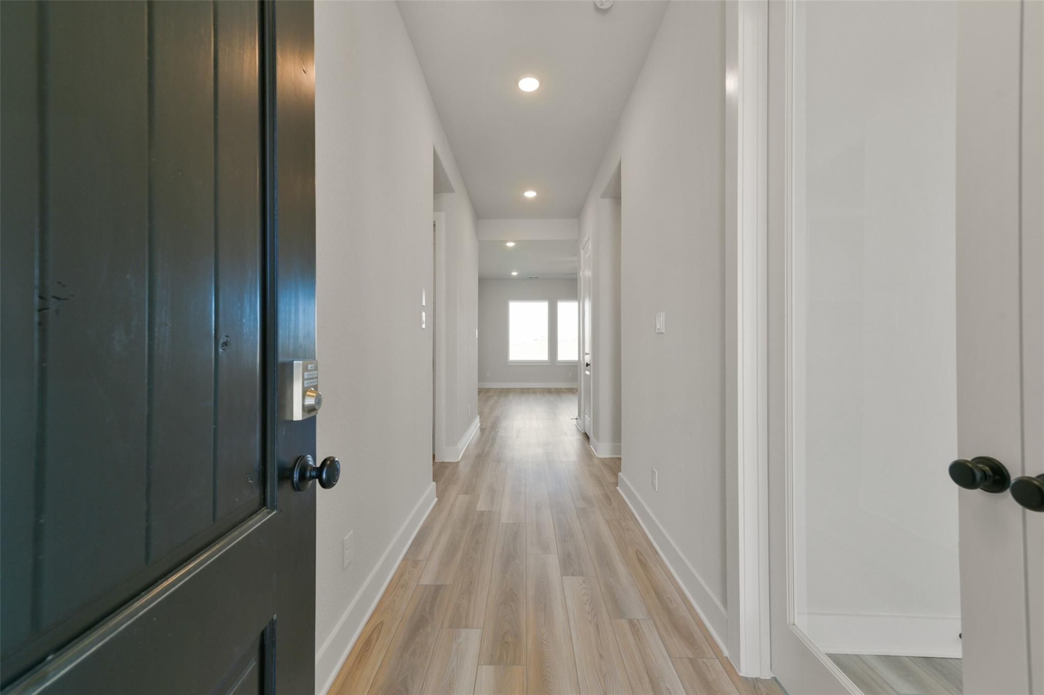 Welcoming entry hallway with light oak floors, white walls, and recessed lights in The Edward C floor plan, Davidson Homes, Lago Mar, Texas City