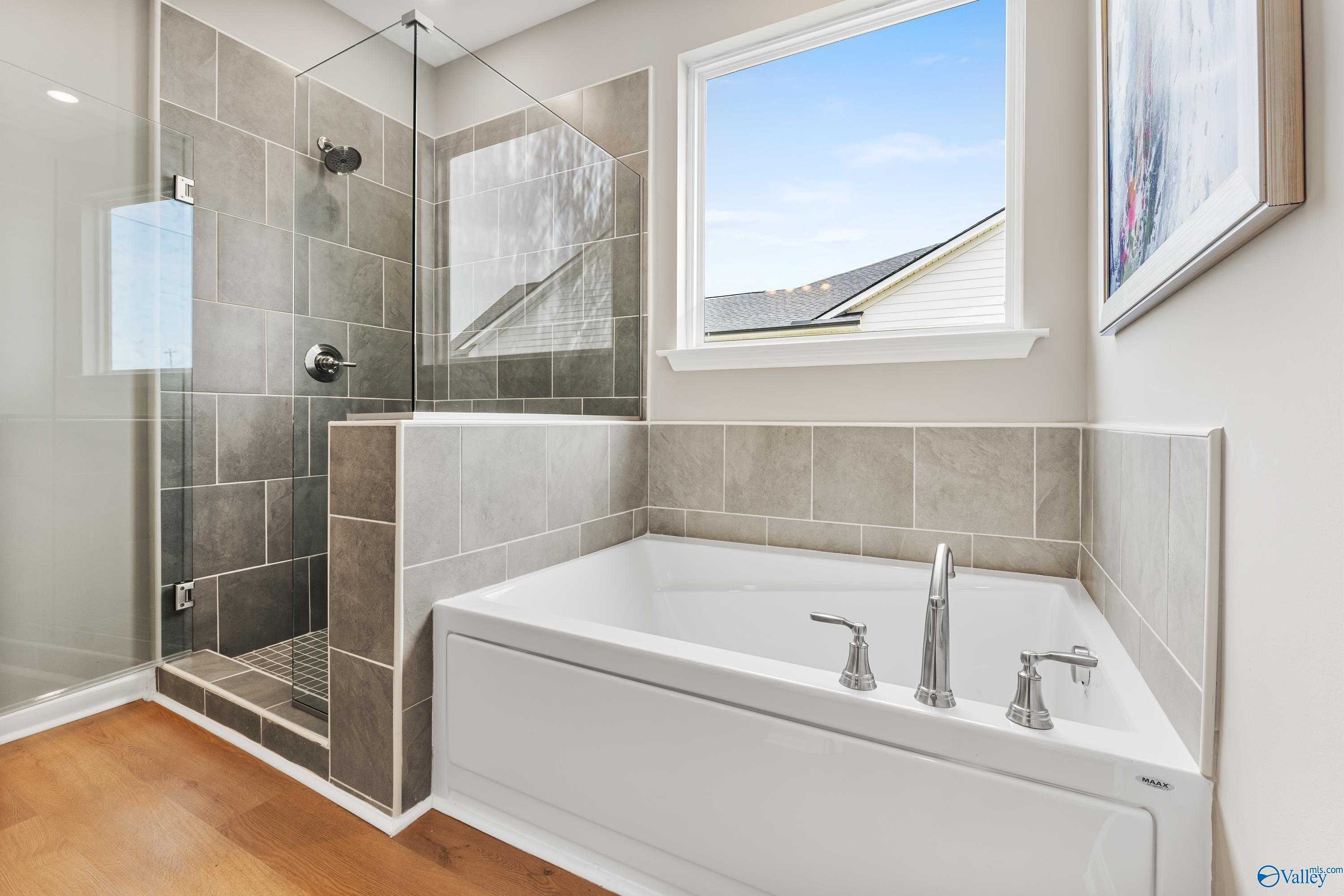 Modern master bathroom with frameless glass shower, soaking tub, and large window in Davidson Homes The Sanctuary, Athens AL