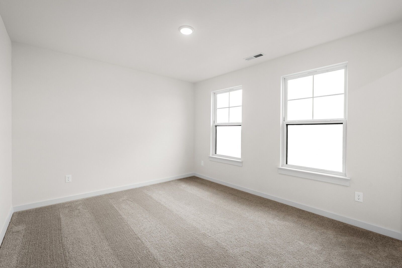 Bright, carpeted bedroom with neutral walls and windows in The Henry C floor plan at Benders Cove, Mt. Juliet, Tennessee.