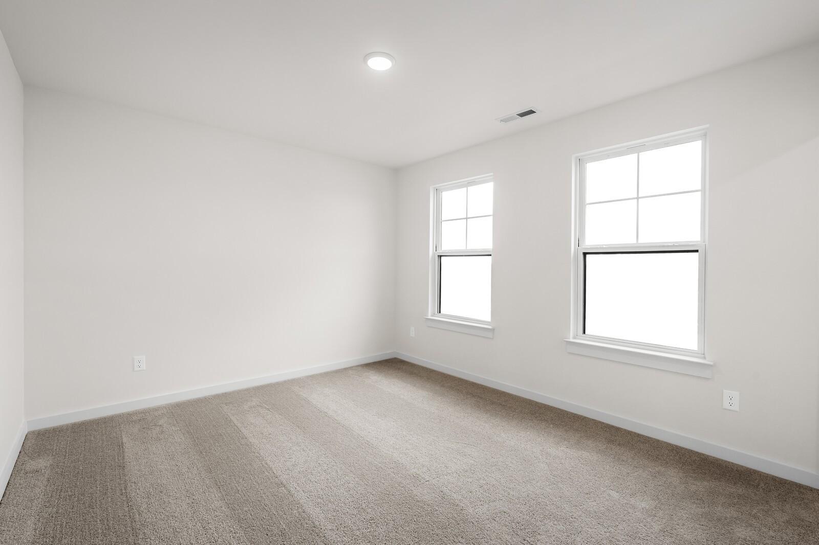 Bright, carpeted bedroom with neutral walls and windows in The Henry C floor plan at Benders Cove, Mt. Juliet, Tennessee.