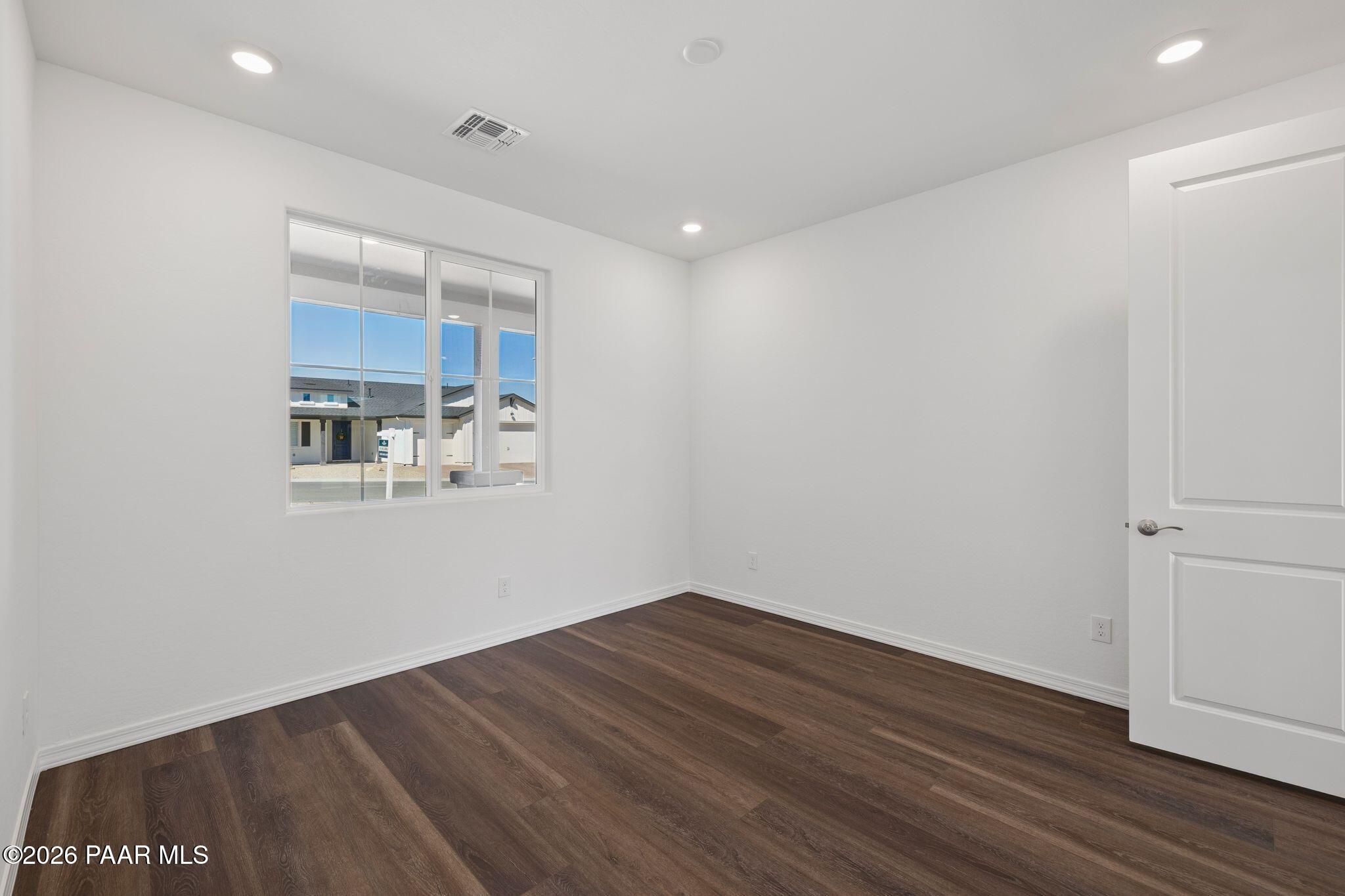 Bright secondary bedroom with large window, hardwood floors and white walls in Davidson Homes The Monarch A, Prescott, Arizona