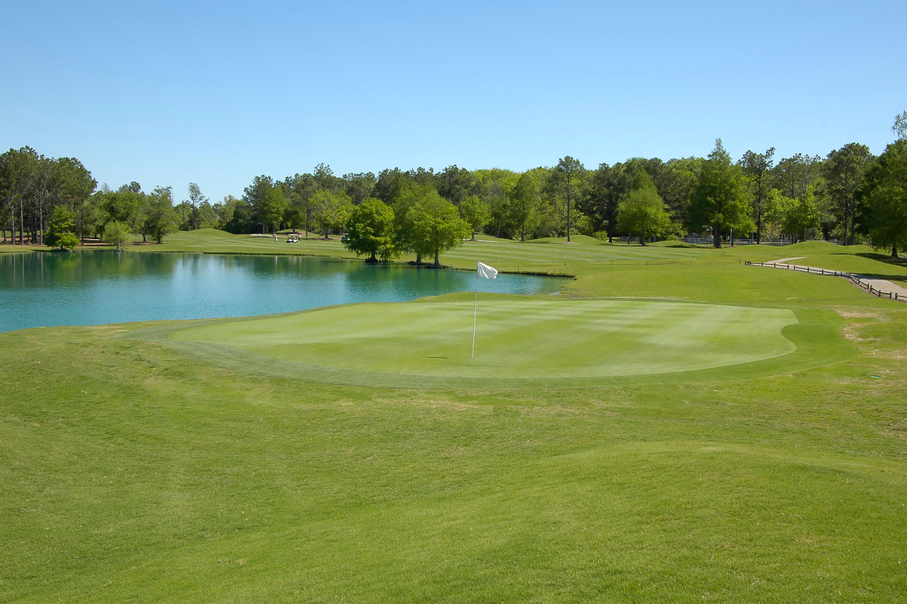 Lush golf green with flagstick beside pond at Little Creek in Arab, Alabama surrounded by trees
