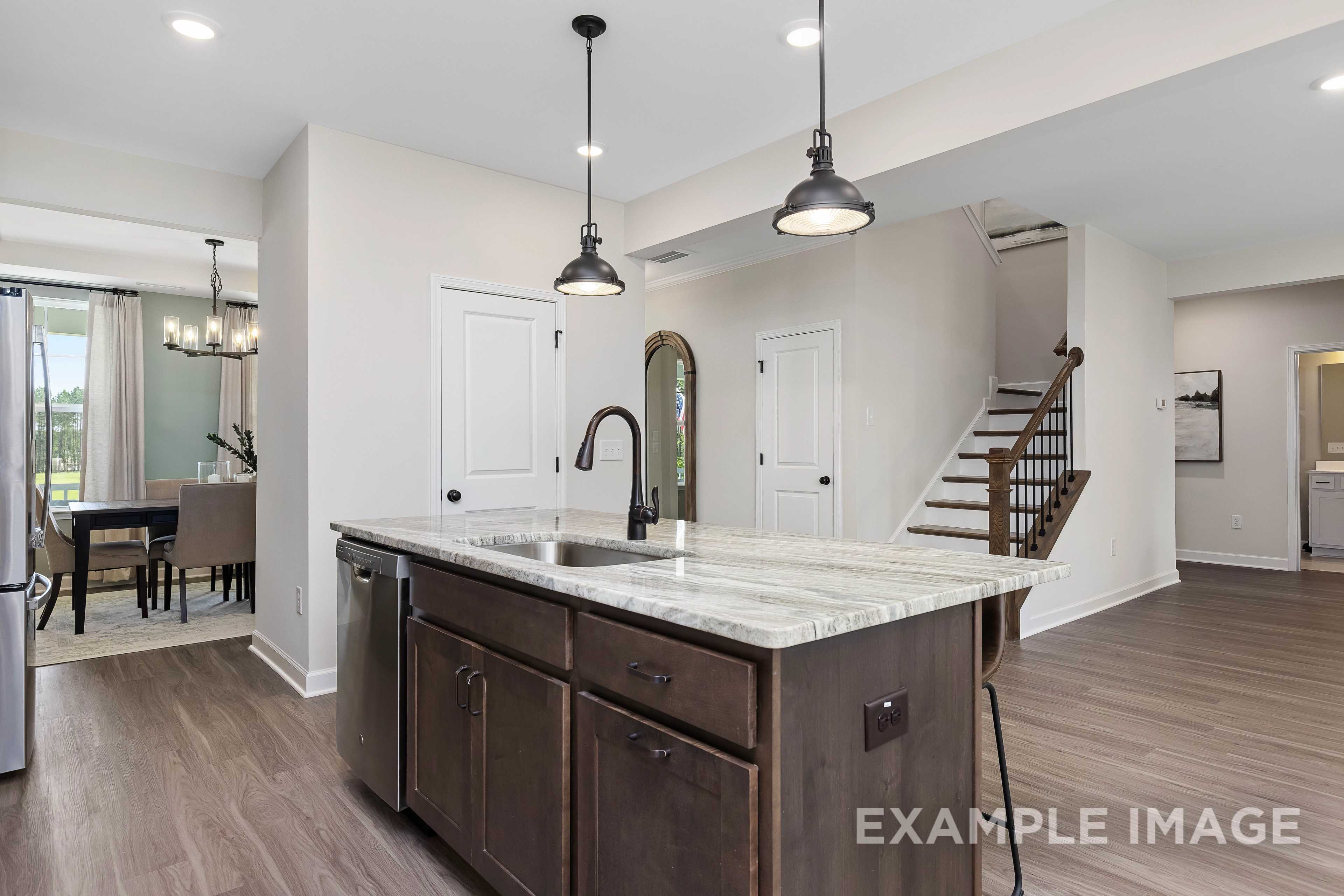 Spacious open-concept kitchen in The Willow B featuring quartz island, dark shaker cabinets, and dining nook