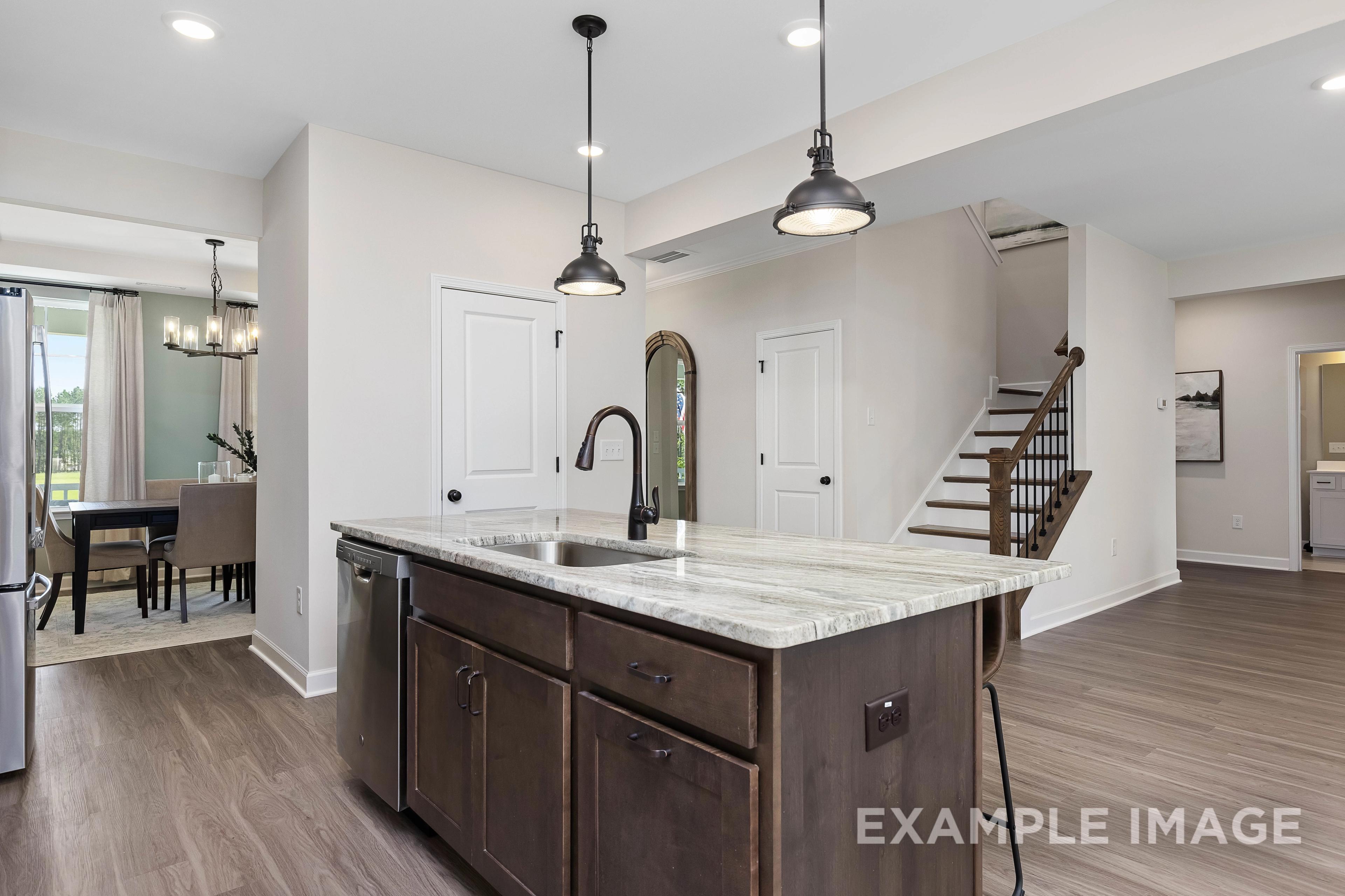 Spacious open-concept kitchen in The Willow B featuring quartz island, dark shaker cabinets, and dining nook