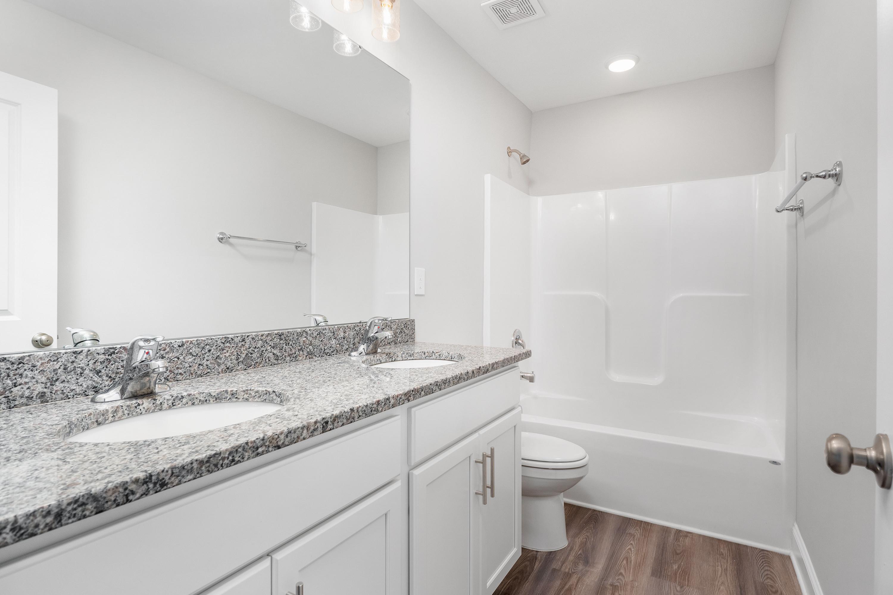 Spacious master bathroom in The Aiken by Davidson Homes featuring double granite vanity, soaking tub, walk-in shower