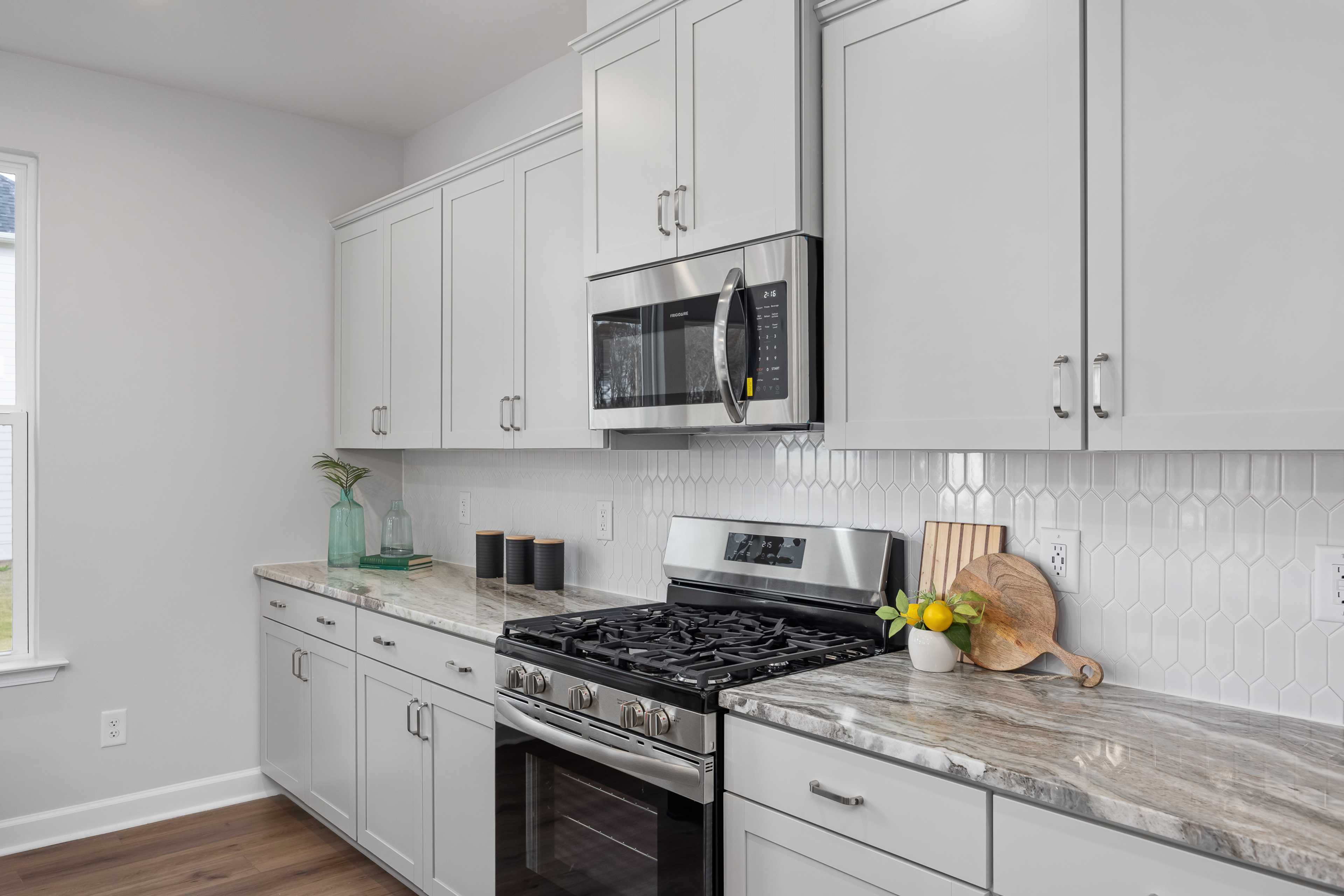 Modern white shaker kitchen at Enclave at Belmont in Belmont NC with stainless steel appliances, quartz counters, herringbone backsplash