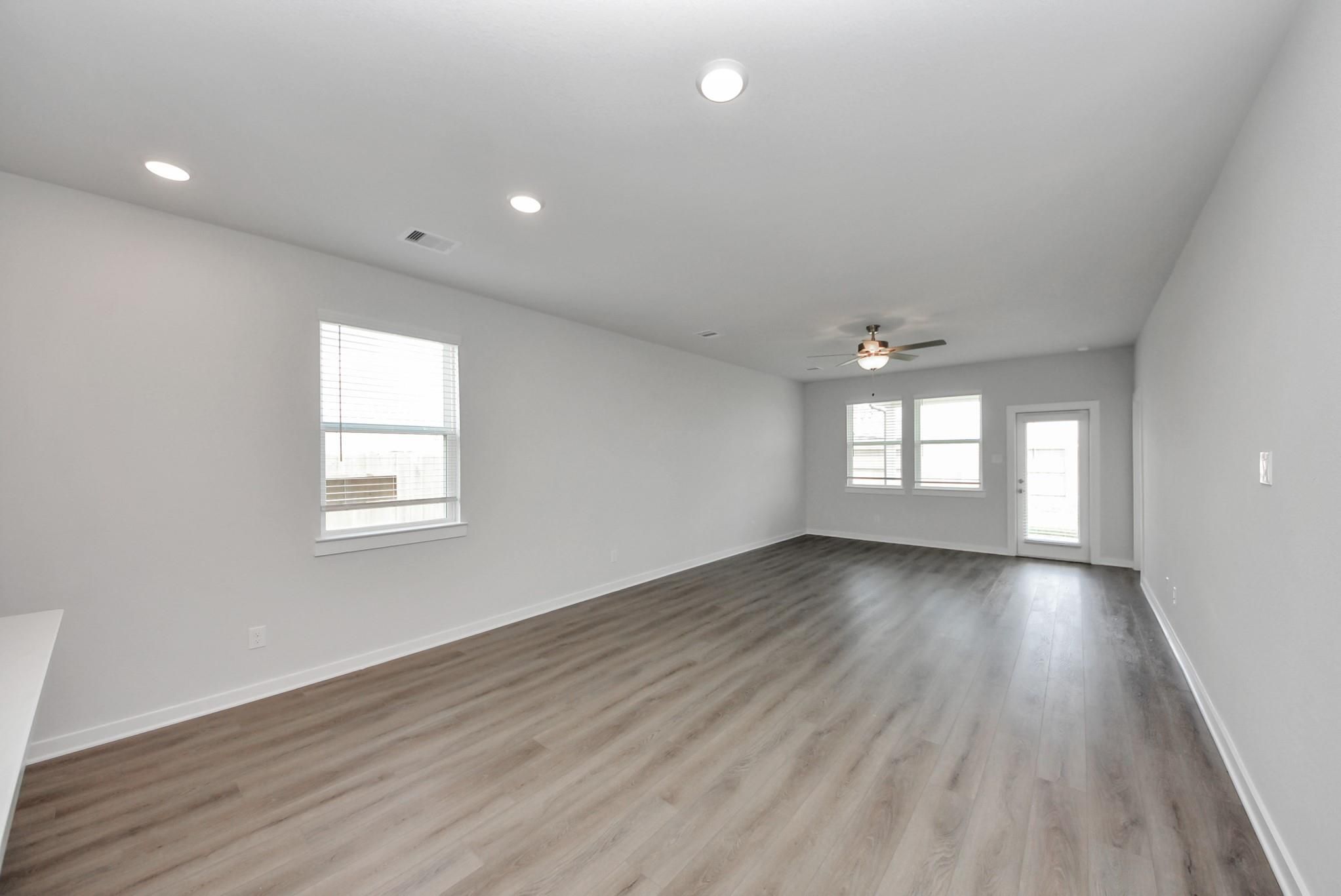 Bright open-concept living area with luxury vinyl plank flooring, recessed lighting, and ceiling fan in Davidson Homes' San Marcos E, Beasley, TX