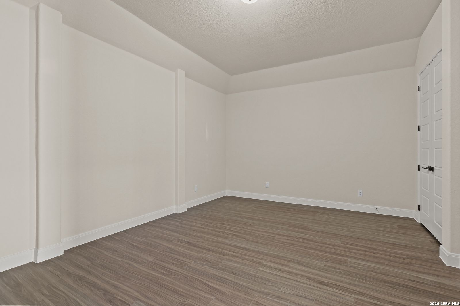Spacious bedroom with wood-look flooring and tray ceiling in The Summerlin B floor plan at Potranco Oaks, Castroville.