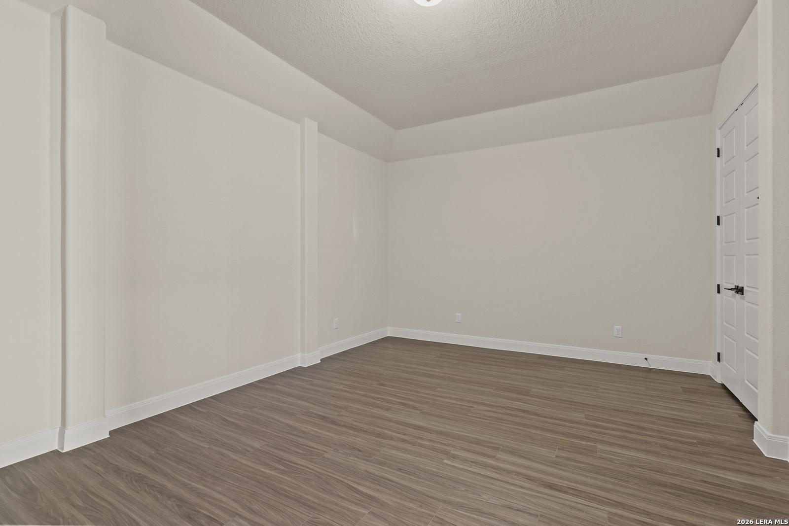 Spacious bedroom with wood-look flooring and tray ceiling in The Summerlin B floor plan at Potranco Oaks, Castroville.