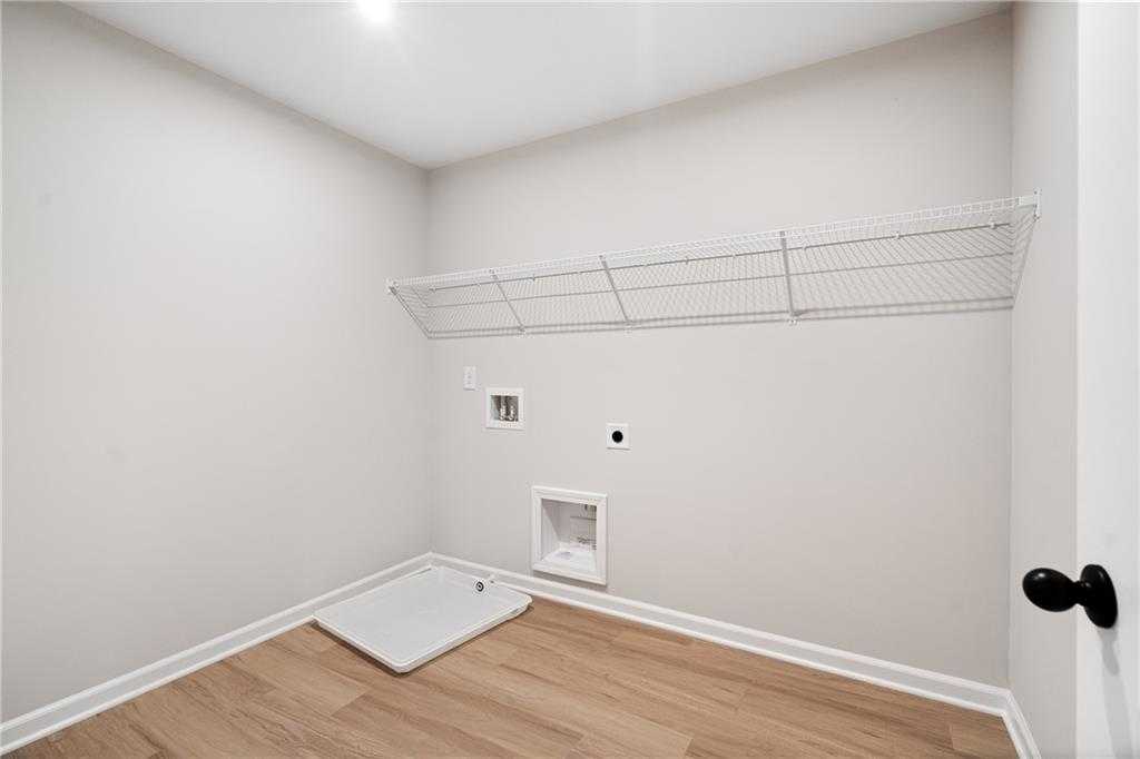 Spacious laundry room with wire shelving, washer hookups, and hardwood floors in Davidson Homes The Marion A, Kennesaw, GA