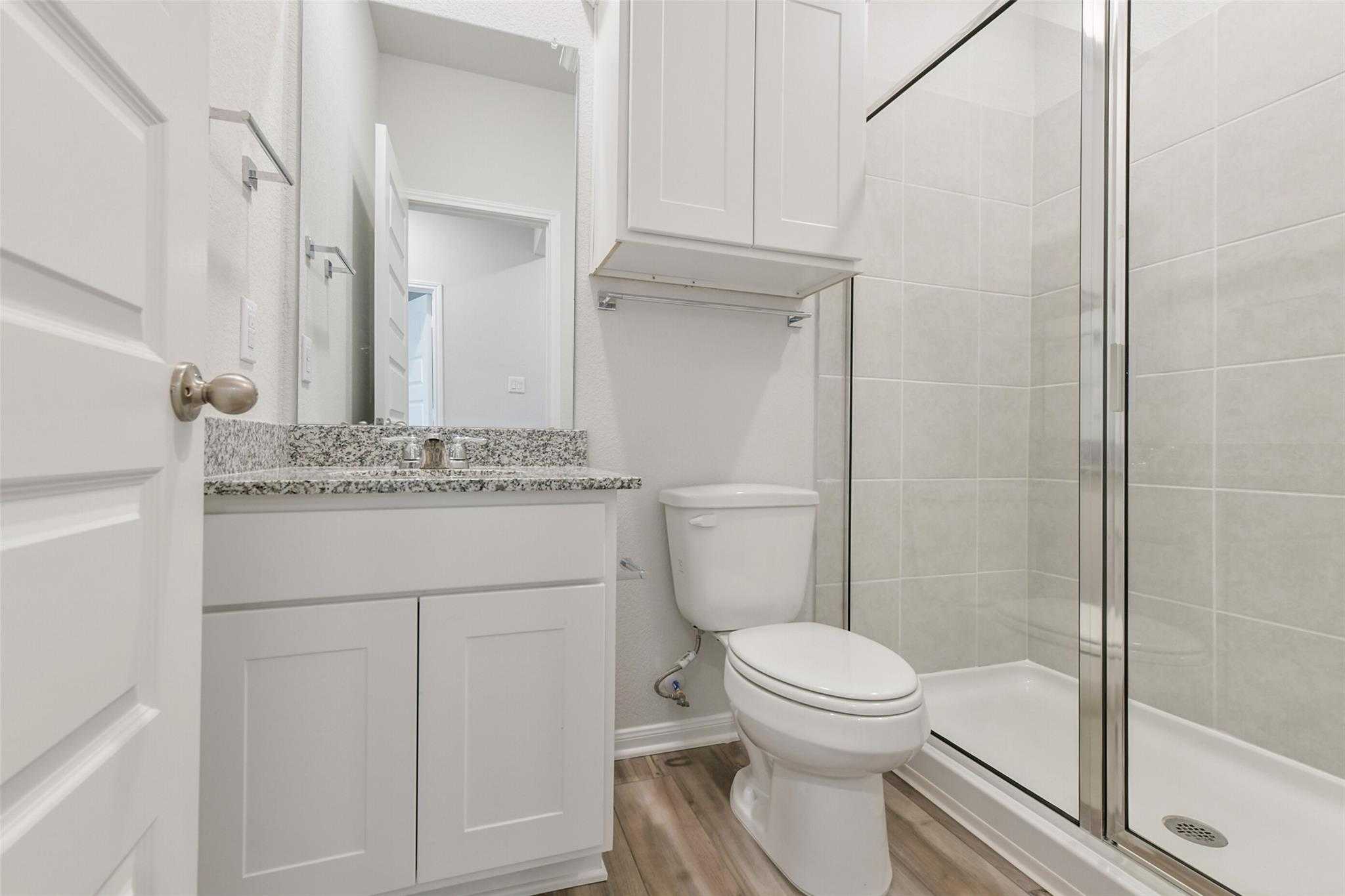 Modern bathroom with white granite vanity, glass shower, and subway tile in The Frio G floor plan, Conroe, Texas