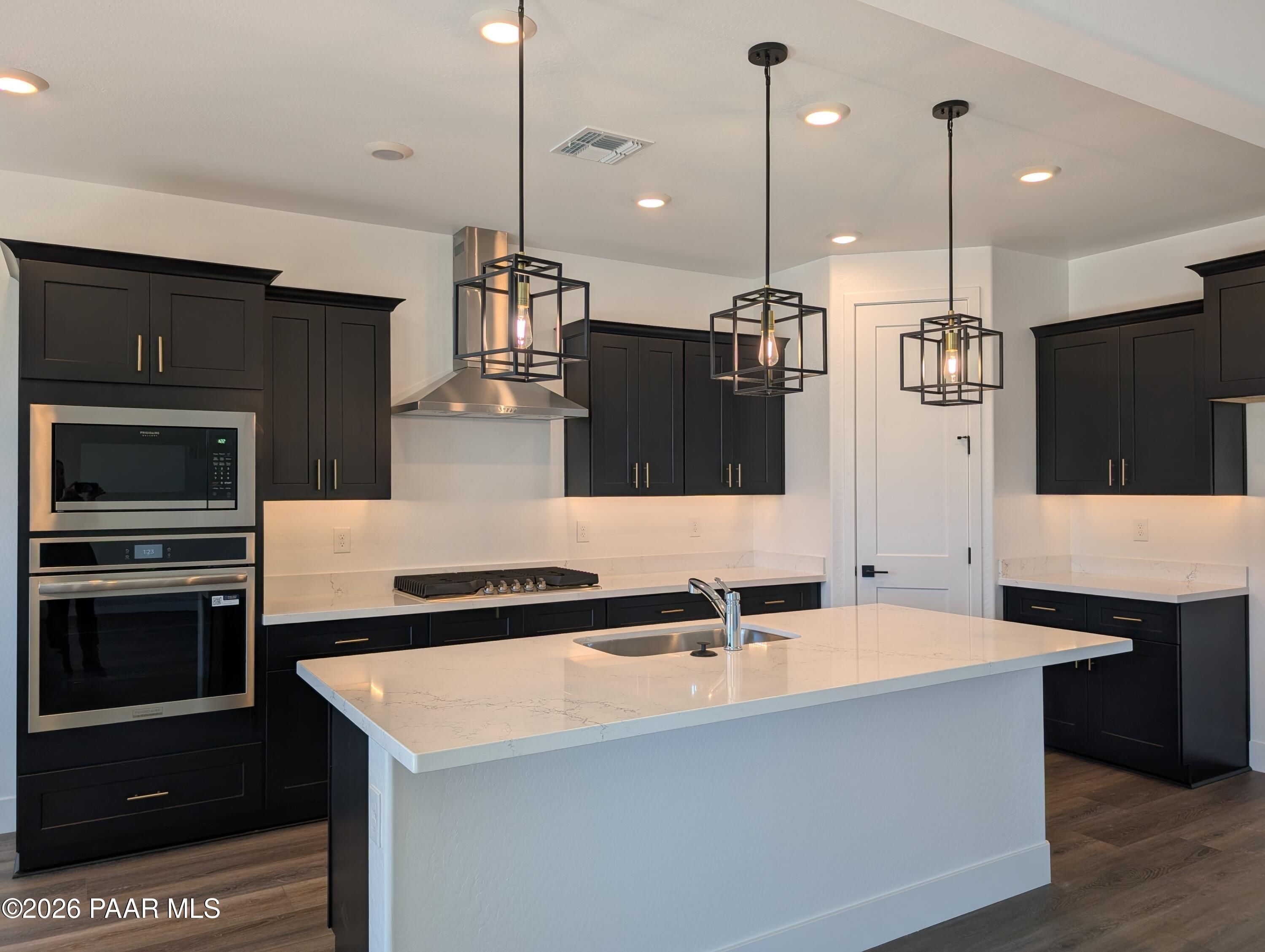 Modern kitchen featuring dark cabinets, white quartz island, stainless appliances, pendant lights in The Sheridan II G, Prescott AZ