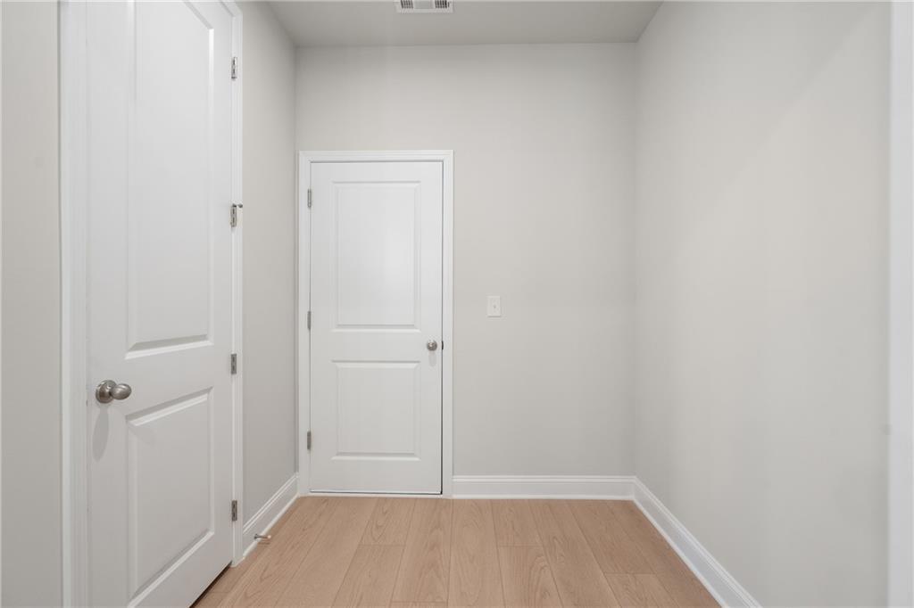 Bright secondary bedroom with light gray walls, oak hardwood floors, white paneled doors in The Hickory E, Buford, GA