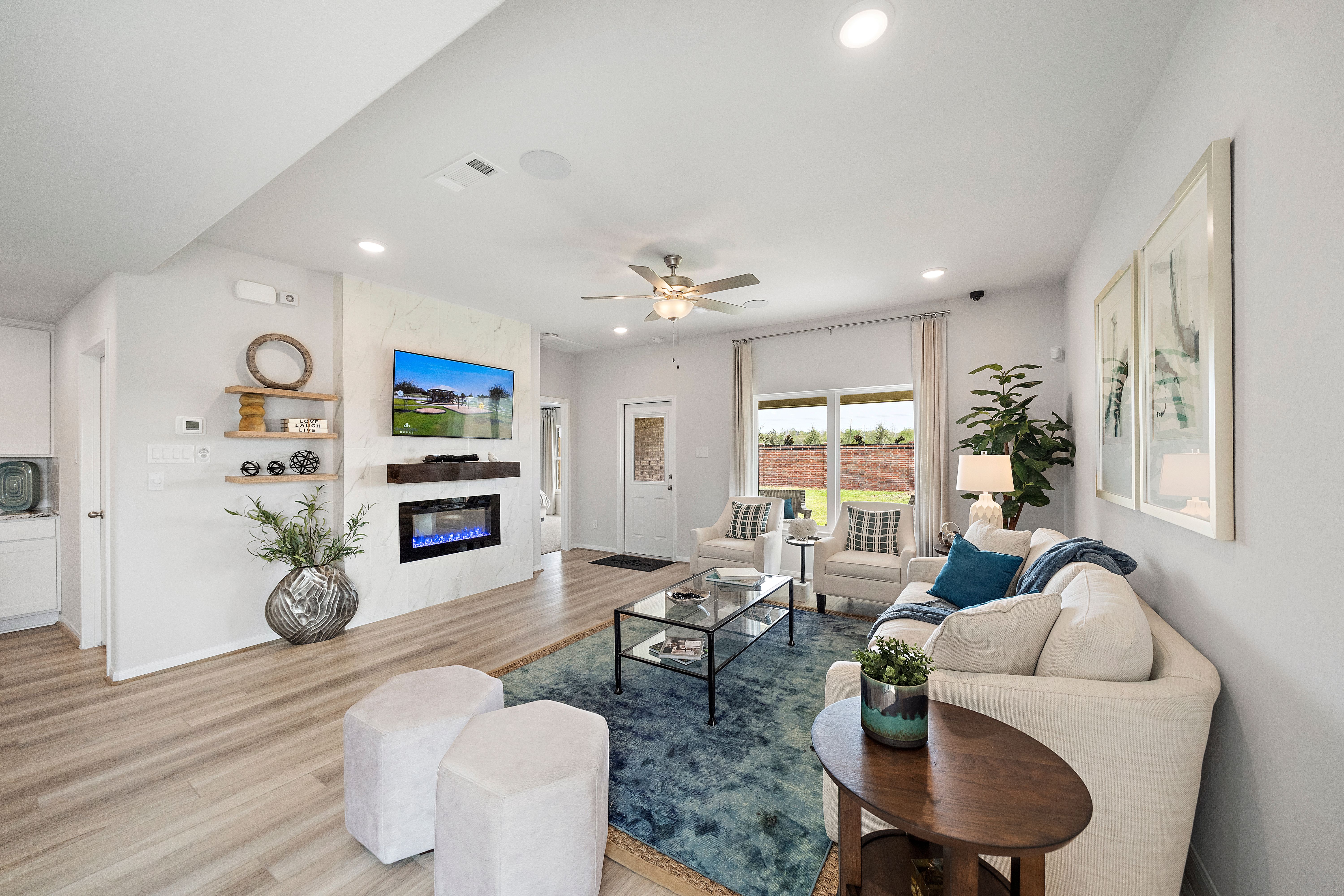 Open-concept living room in Sunterra Katy Texas by Davidson Homes with gas fireplace TV dining area and modern seating