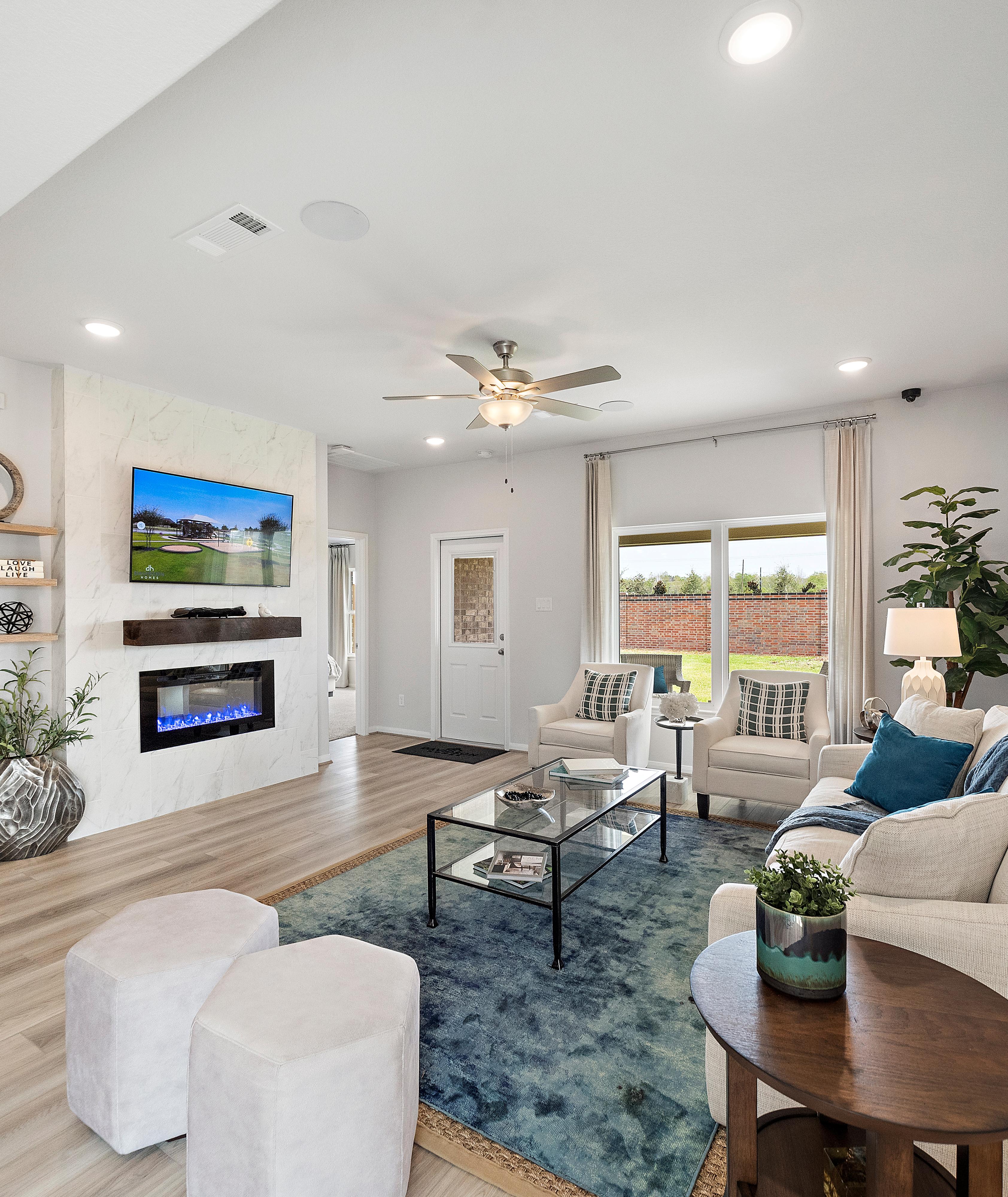 Open-concept living room in Sunterra Katy Texas by Davidson Homes with gas fireplace TV dining area and modern seating