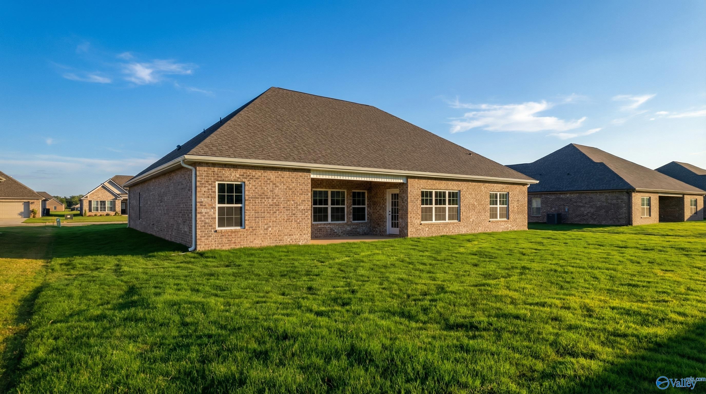 Rear view of The Finleigh 3-bedroom brick home by Davidson Homes with covered patio and lush green lawn in Briercreek, Meridianville, Alabama