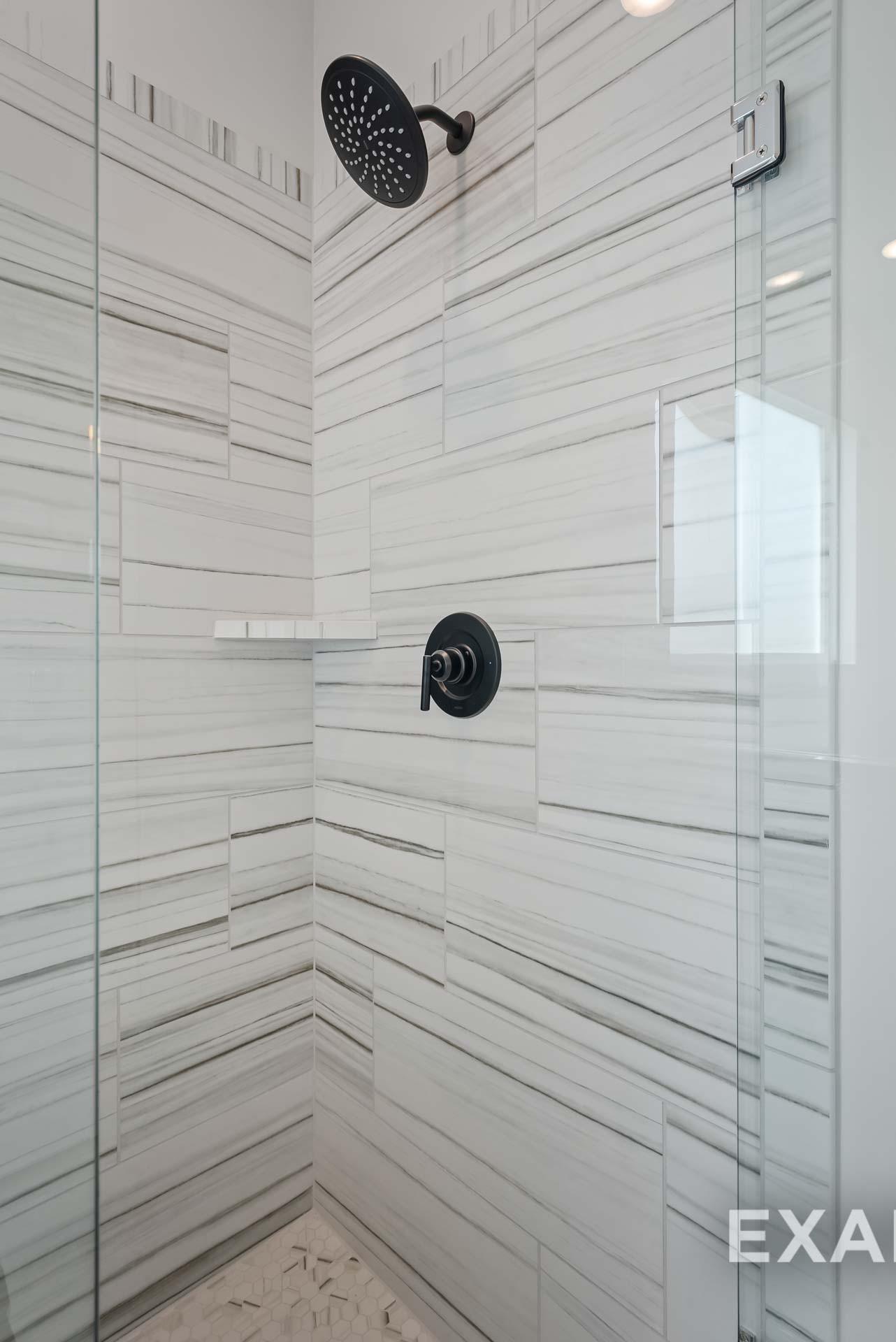Elegant frameless glass walk-in shower with white subway tiles, rainfall showerhead, and niche shelf in Davidson Homes The Ridgeport master bath, Gallatin, TN