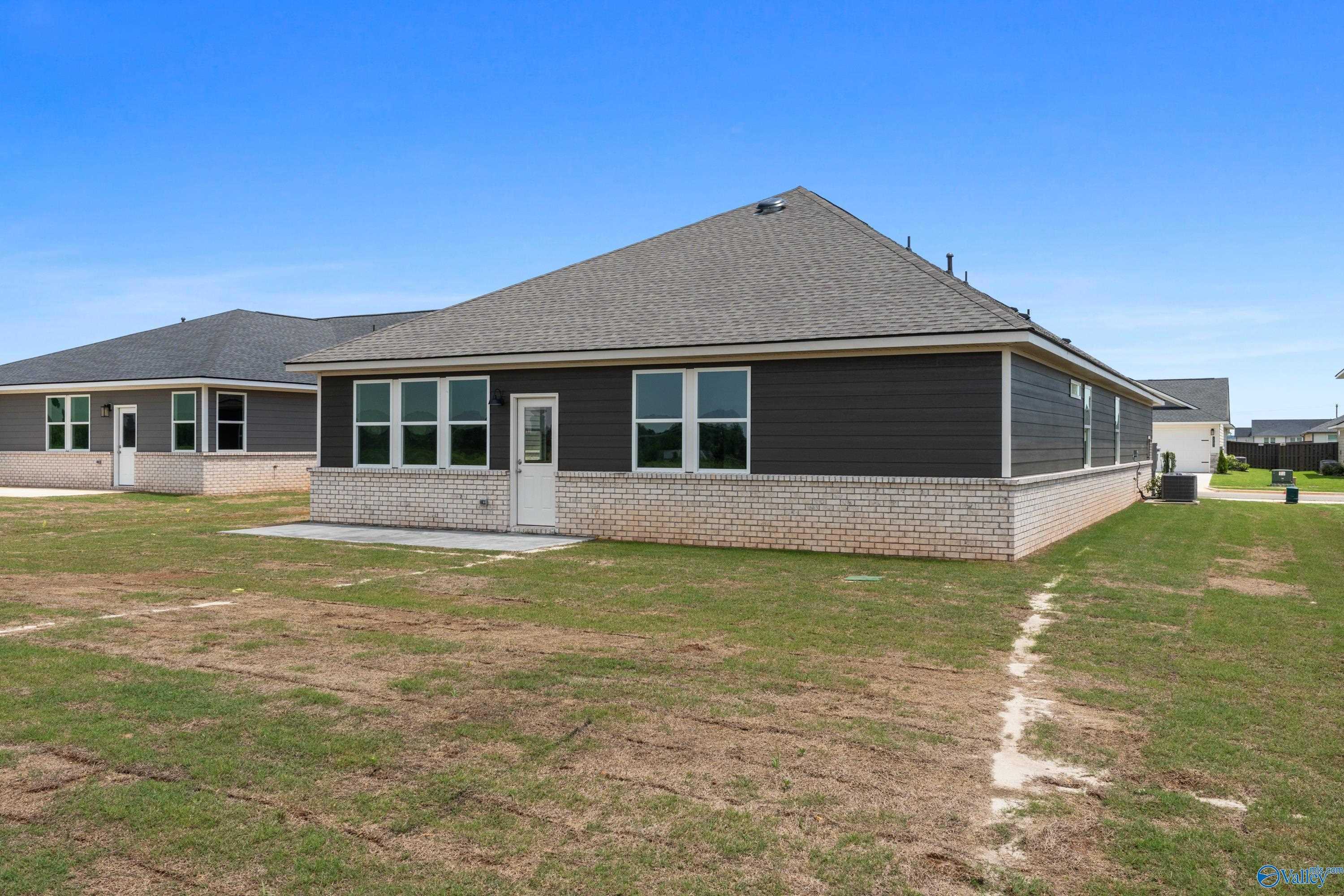 Modern single-story 4-bedroom home with gray siding, brick base, and side entrance in Anderson Farm, Athens, Alabama