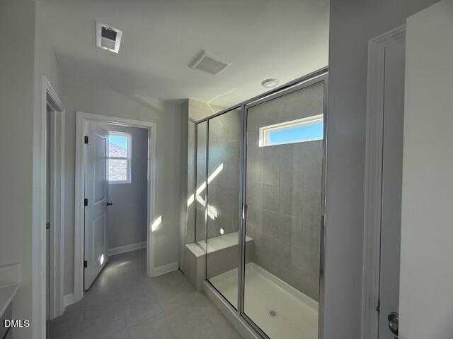 Modern master bathroom with frameless glass shower, tiled bench, and natural light in Davidson Homes The Gavin B, Lillington, NC