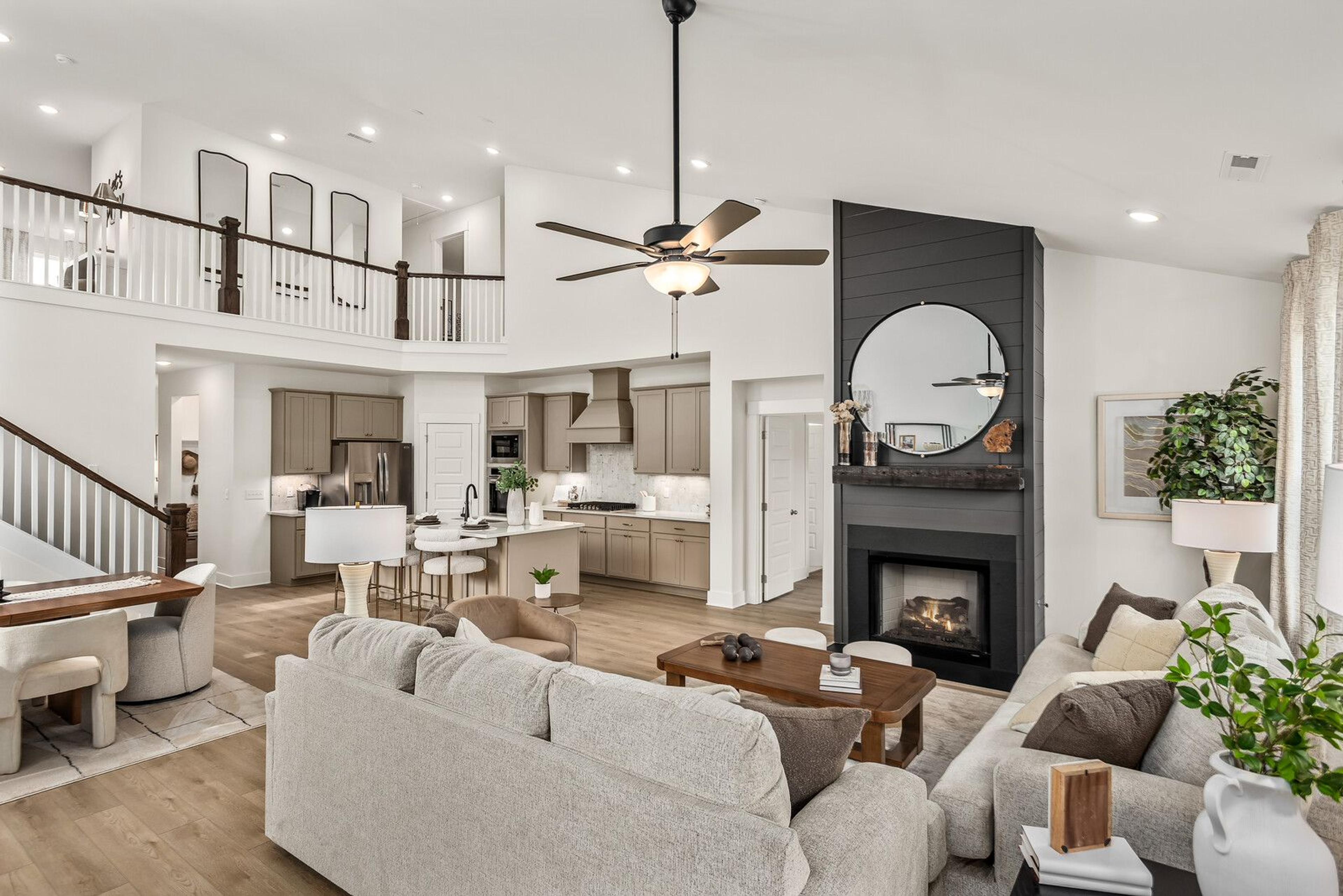 Open-concept living room at Bradshaw Farms in Mt. Juliet, TN, featuring a fireplace, lofted ceiling, and modern kitchen.