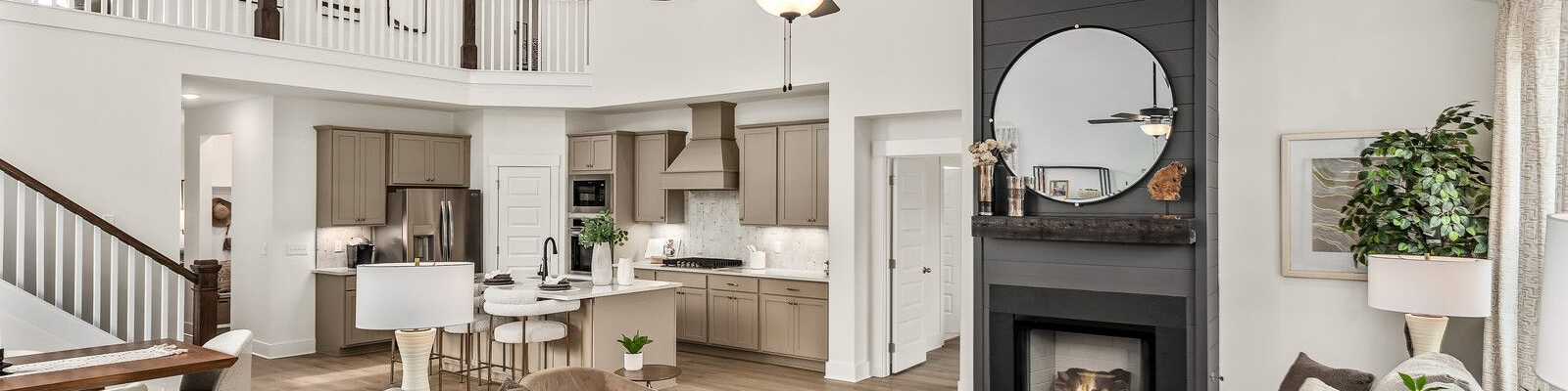 Open-concept living room at Bradshaw Farms in Mt. Juliet, TN, featuring a fireplace, lofted ceiling, and modern kitchen.