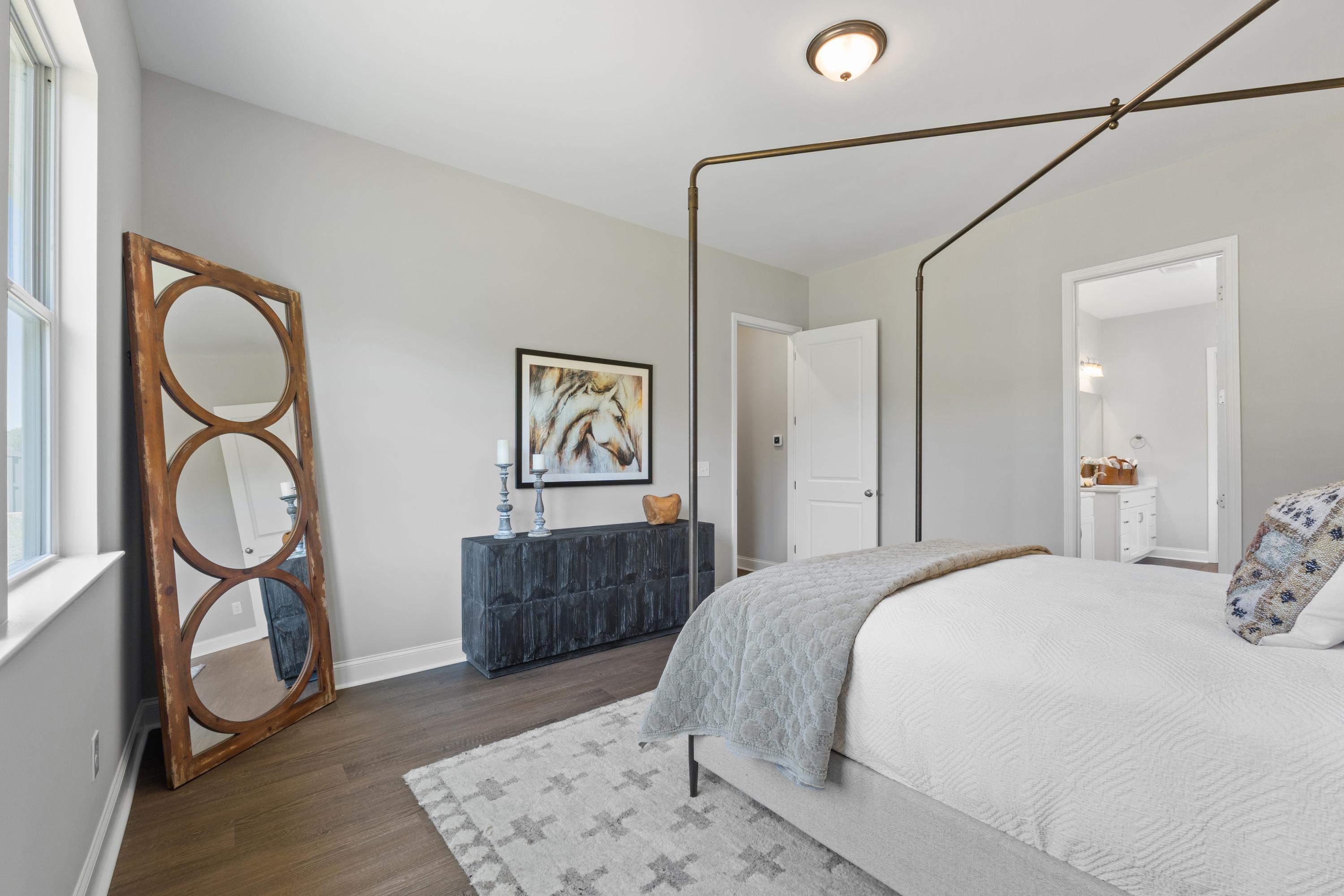 Spacious master suite in The Haven D featuring king bed with gray bedding, arched wood mirror, and en-suite door