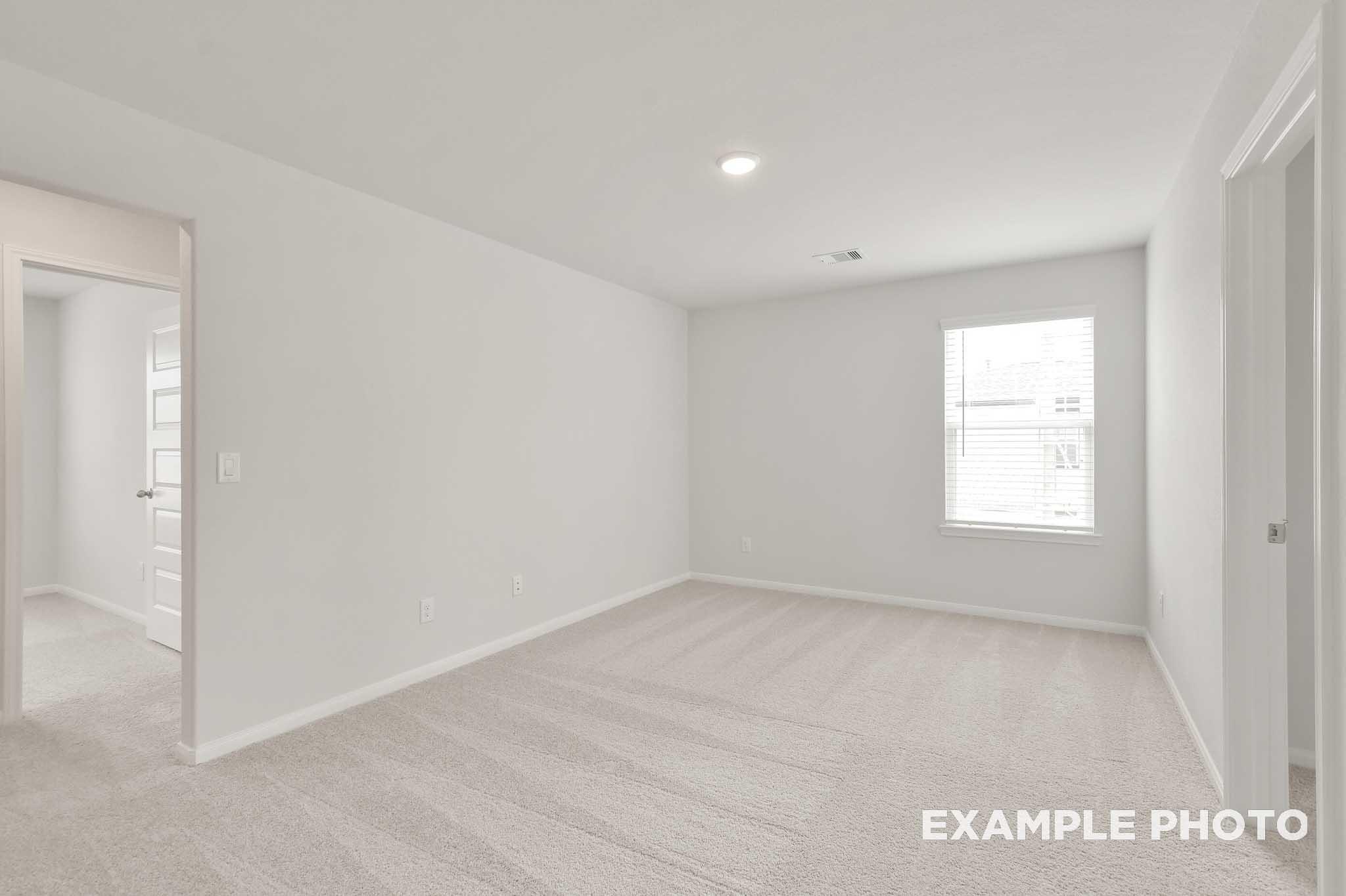 Spacious carpeted bedroom with white walls and window in The Brazos, a Davidson Homes new construction home in Beasley, Texas