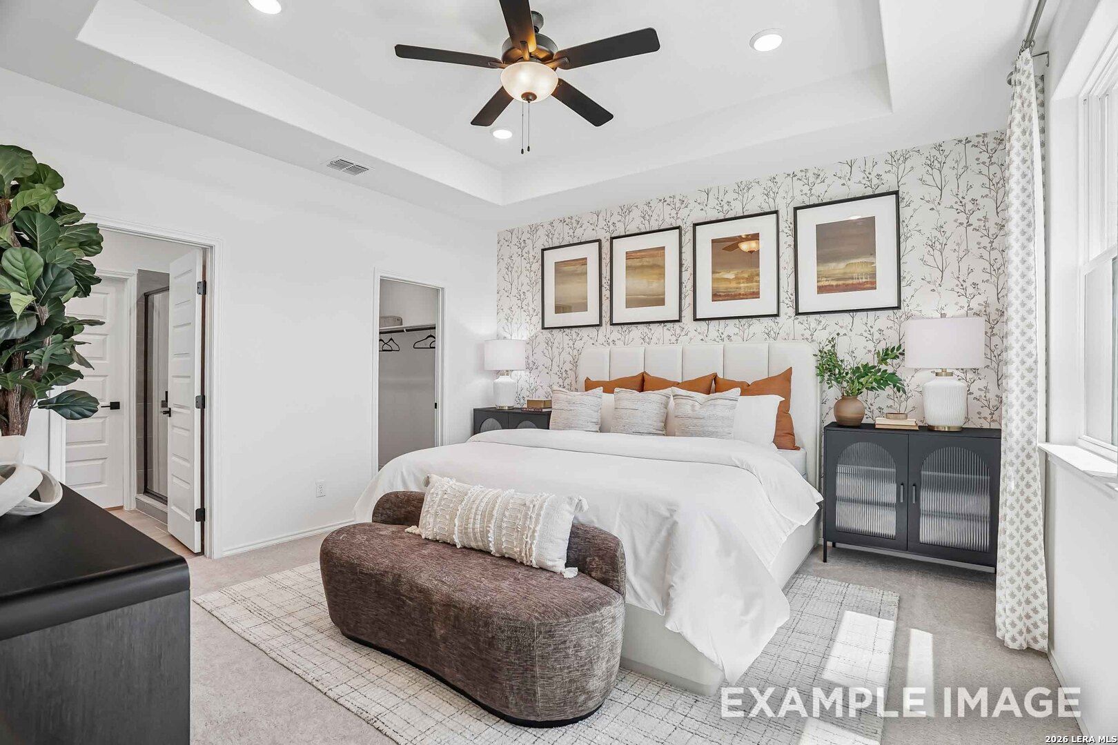 Primary bedroom with tray ceiling, accent wallpaper, and tufted headboard in Davidson Homes Pinecrest E, Converse, Texas