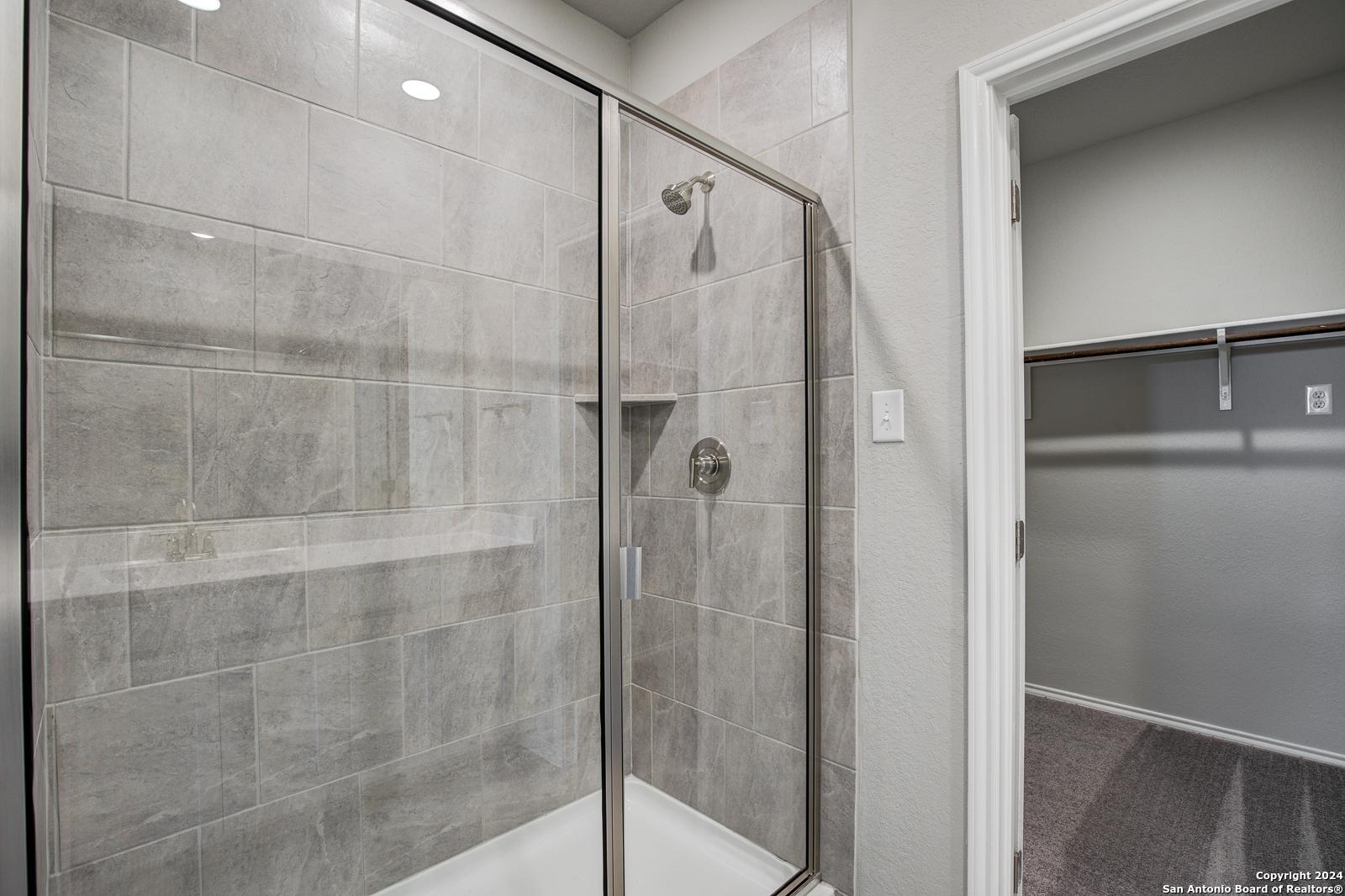 Modern walk-in shower with frameless glass enclosure, gray subway tile, and rainfall head in Davidson Homes The Blanco C master bath, San Antonio