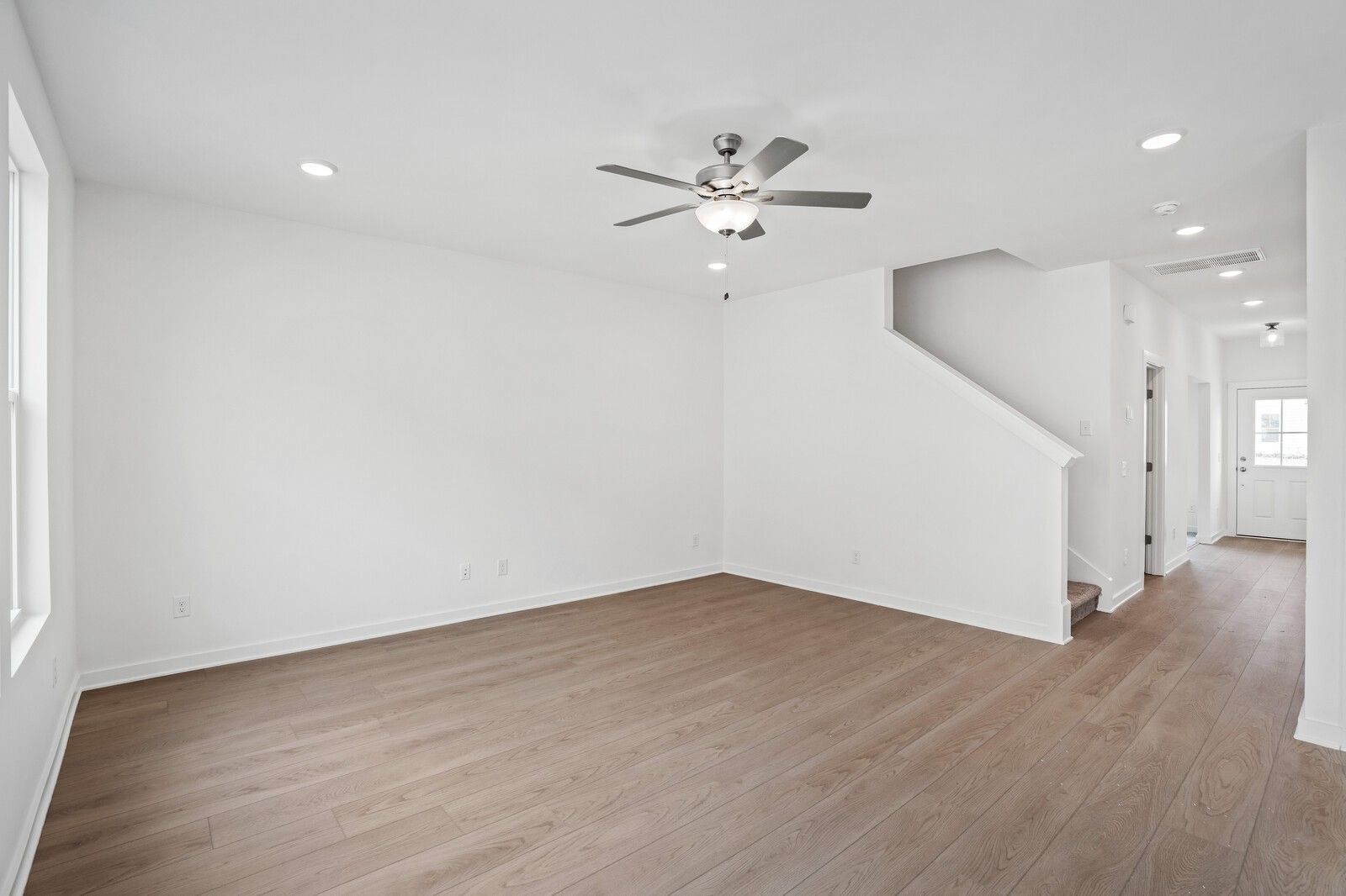 Bright foyer with hardwood floors, ceiling fan, and white staircase in Davidson Homes The Logan B, White House, TN