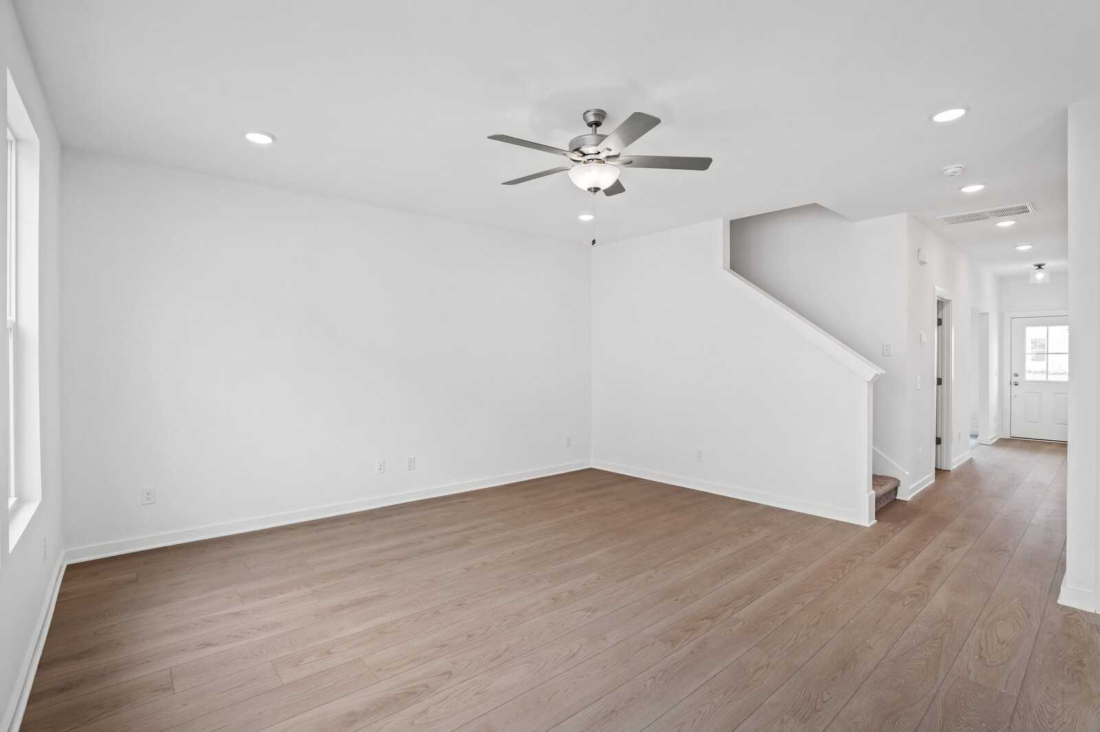 Bright foyer with hardwood floors, ceiling fan, and white staircase in Davidson Homes The Logan B, White House, TN