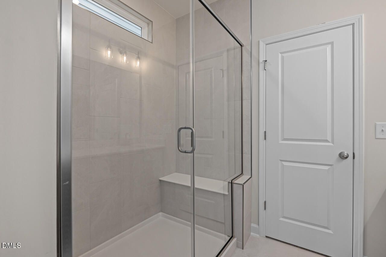 Modern walk-in glass shower with built-in bench in The Ashport G floor plan at Sage on North Main, Wake Forest, NC.