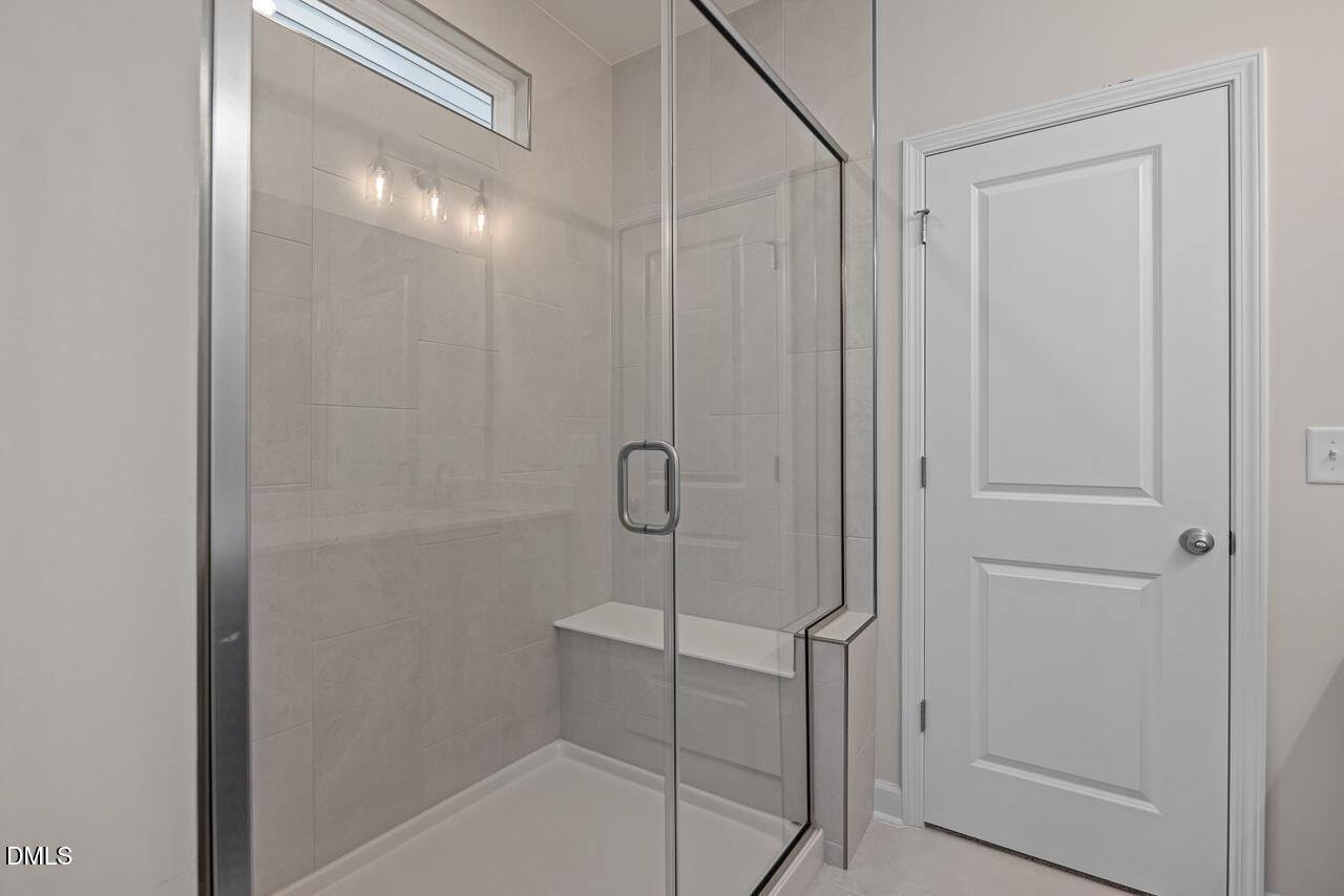 Modern walk-in glass shower with built-in bench in The Ashport G floor plan at Sage on North Main, Wake Forest, NC.