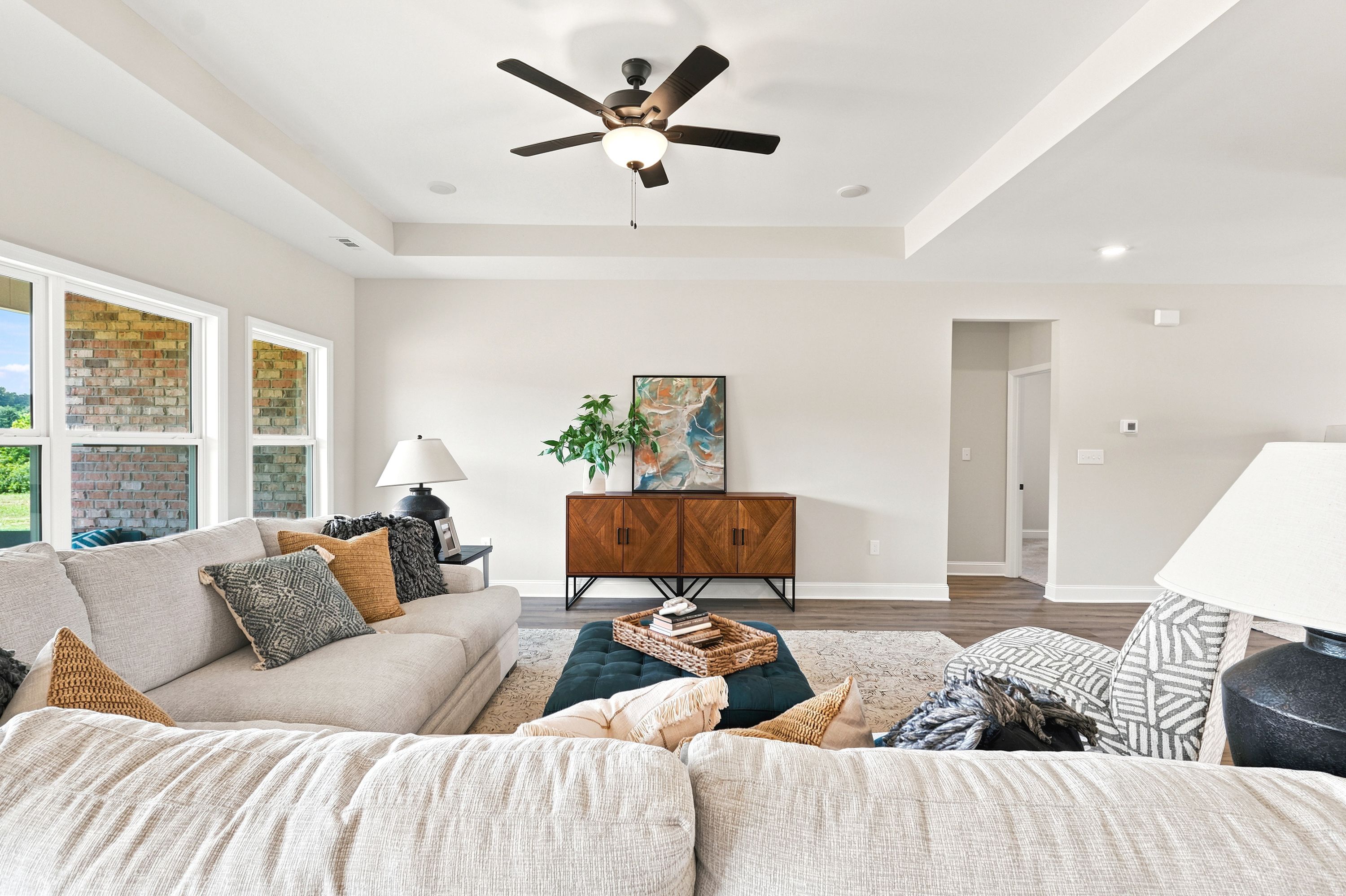 Spacious living room at Riverton Preserve in Huntsville, AL featuring a tray ceiling, plush sectional, and modern decor.