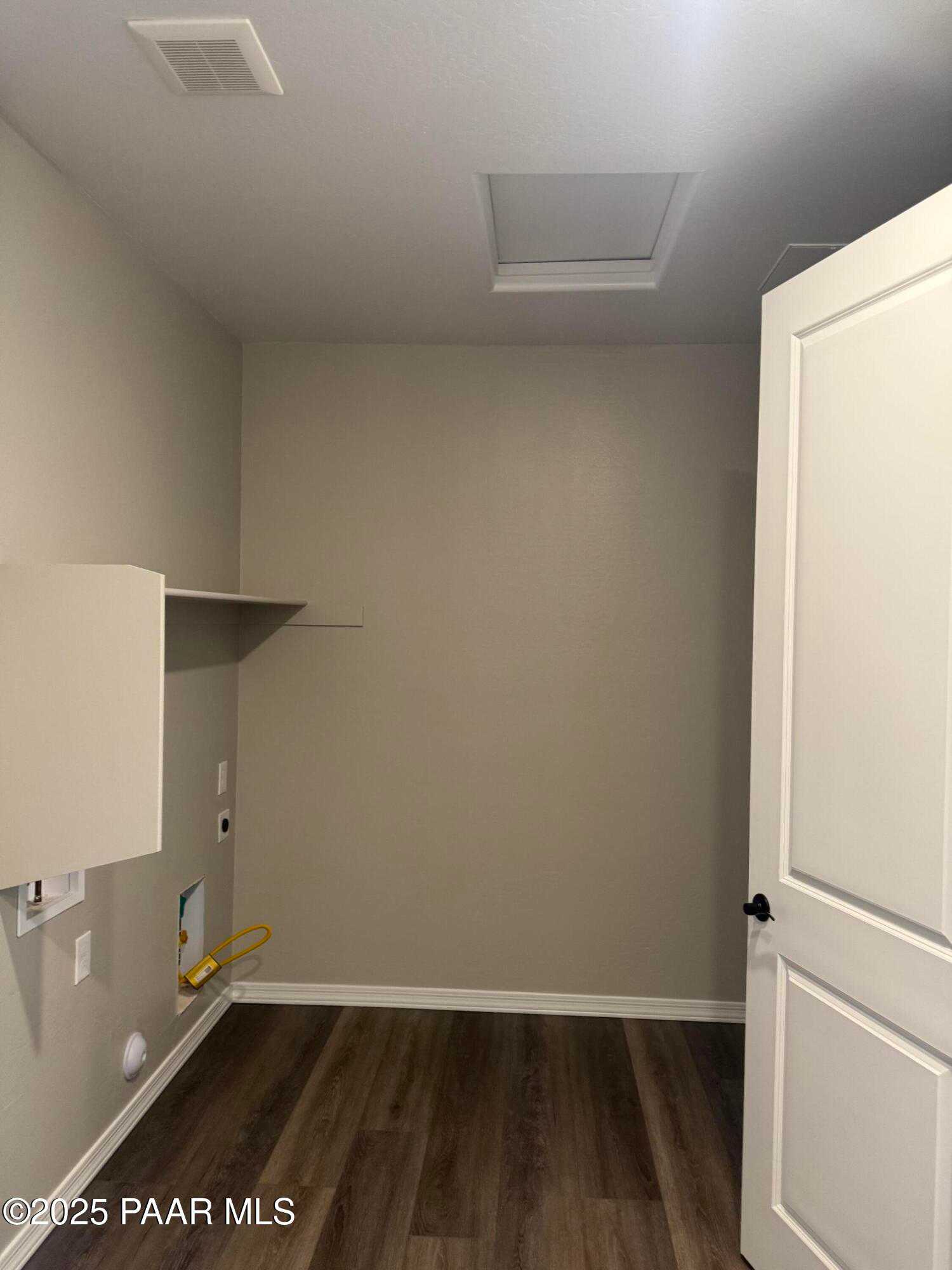 Modern laundry room with wood laminate flooring, utility hookups, built-in cabinet, and skylight in Davidson Homes Durango II A, Prescott AZ