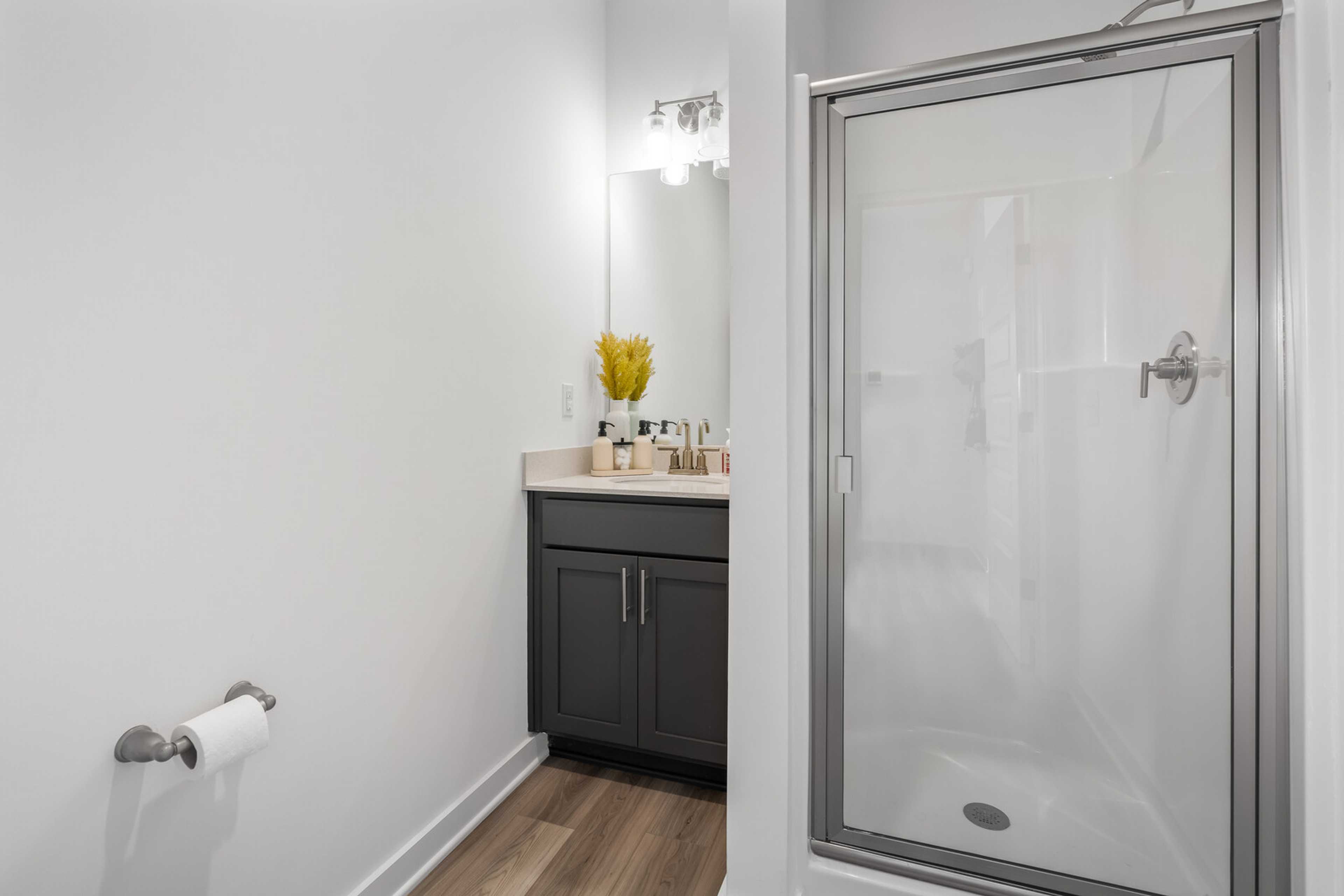 Modern bathroom at The Towns at Red River in Gallatin TN with gray vanity, glass shower, and hardwood floors