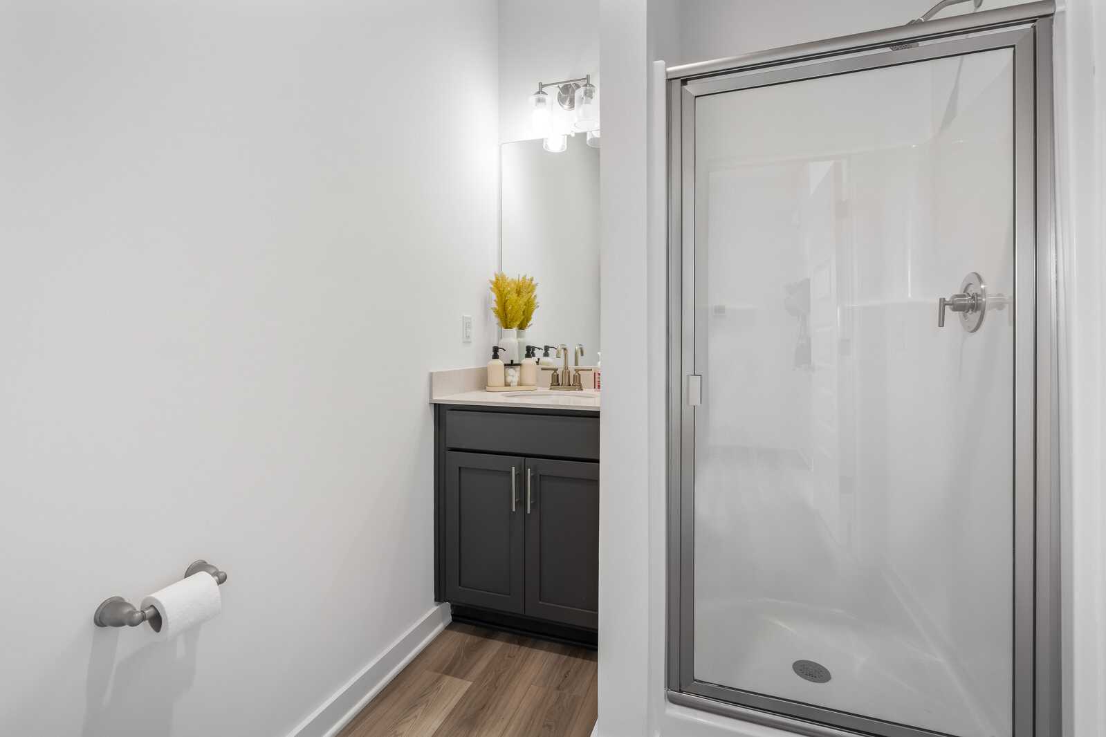 Modern bathroom at The Towns at Red River in Gallatin TN with gray vanity, glass shower, and hardwood floors