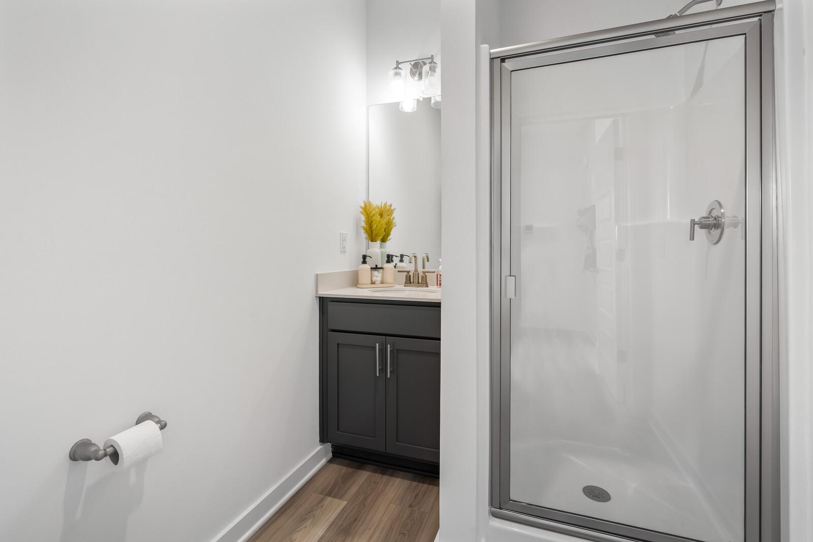 Modern bathroom at The Towns at Red River in Gallatin TN with gray vanity, glass shower, and hardwood floors