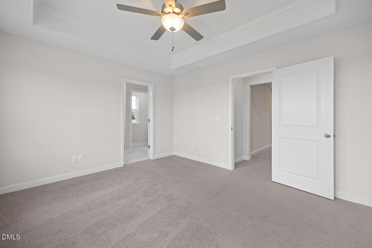 Spacious bedroom with tray ceiling, ceiling fan, and plush carpet in Davidson Homes' The Mitchell plan, Knightdale, NC