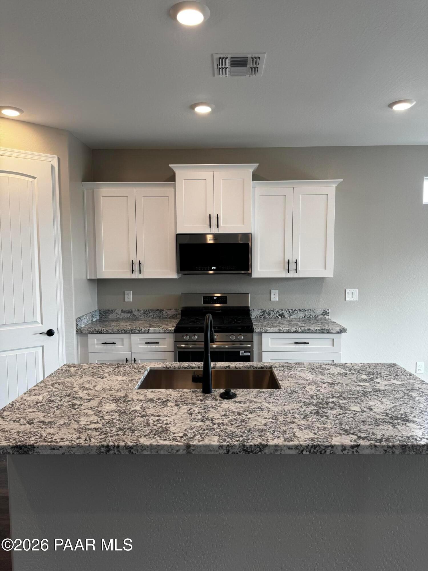 Modern kitchen with white shaker cabinets, quartz island sink, stainless steel appliances in Durango II B, Prescott AZ